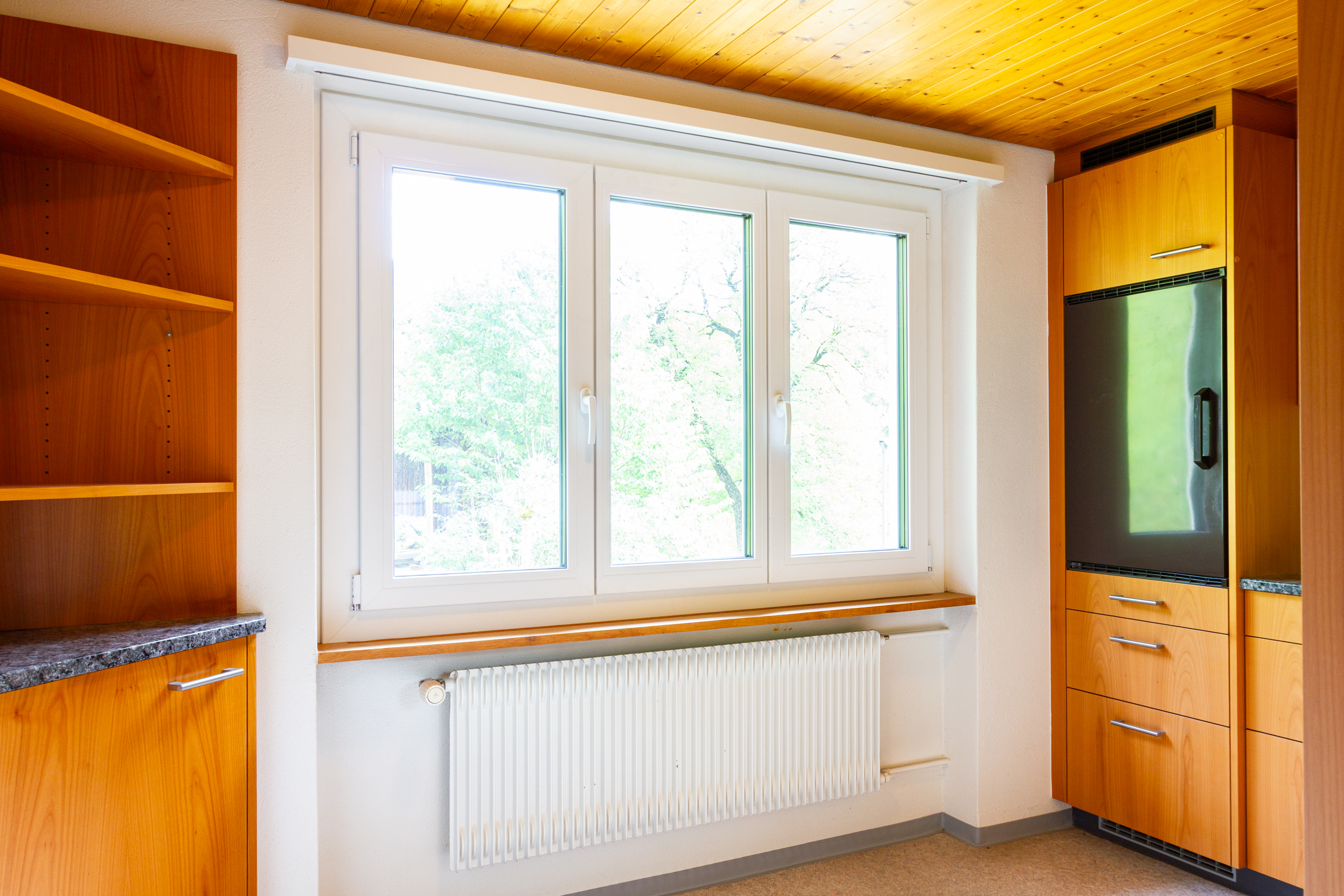 Helle Einbauküche mit Fenster und Holzfronten