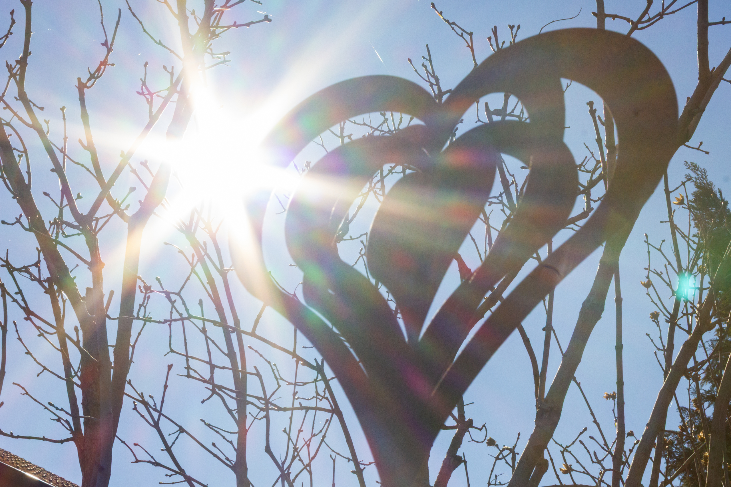 Dekoratives Herz vor sonnigem Himmel