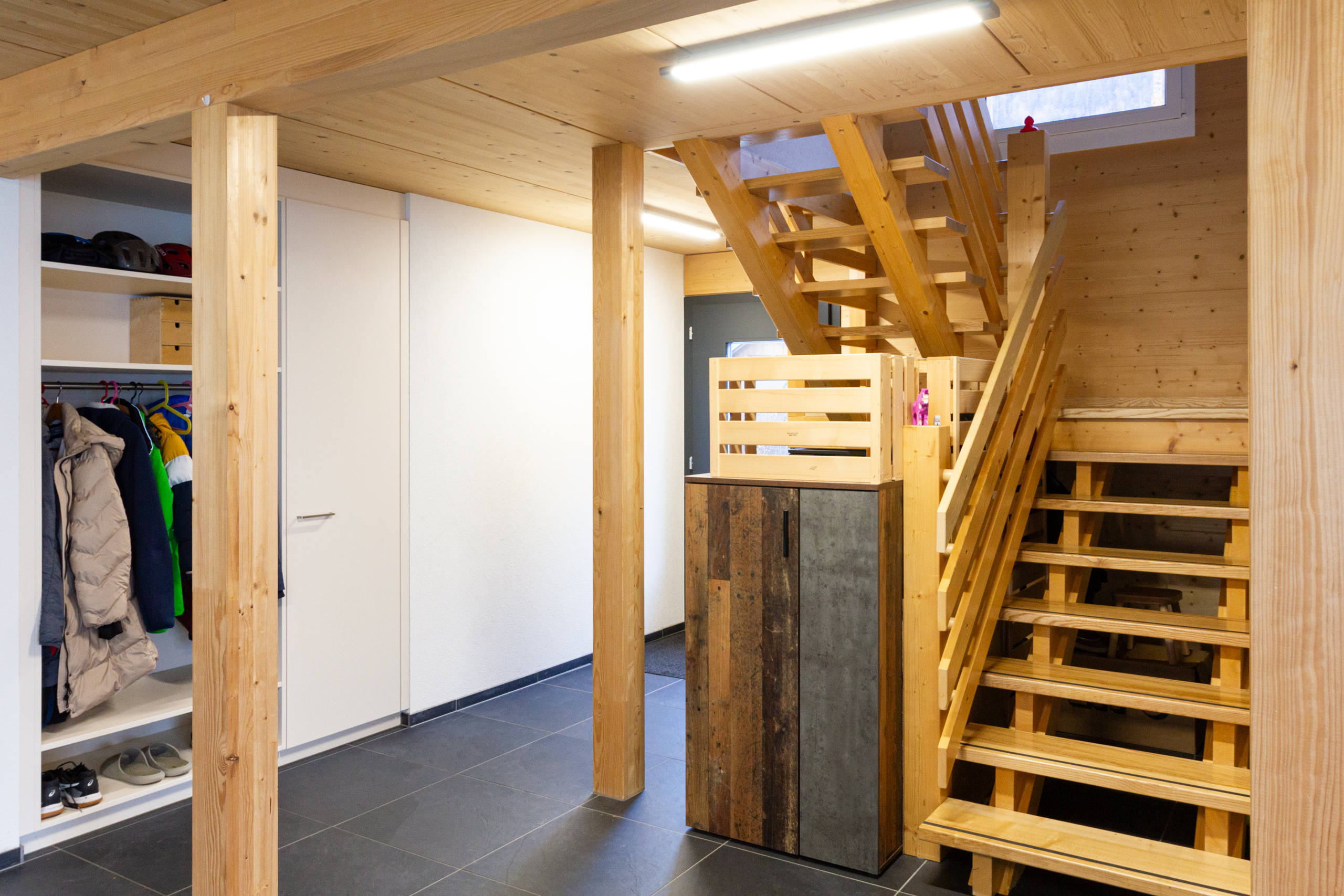 Moderner Eingangs- und Garderobenbereich mit Holztreppe