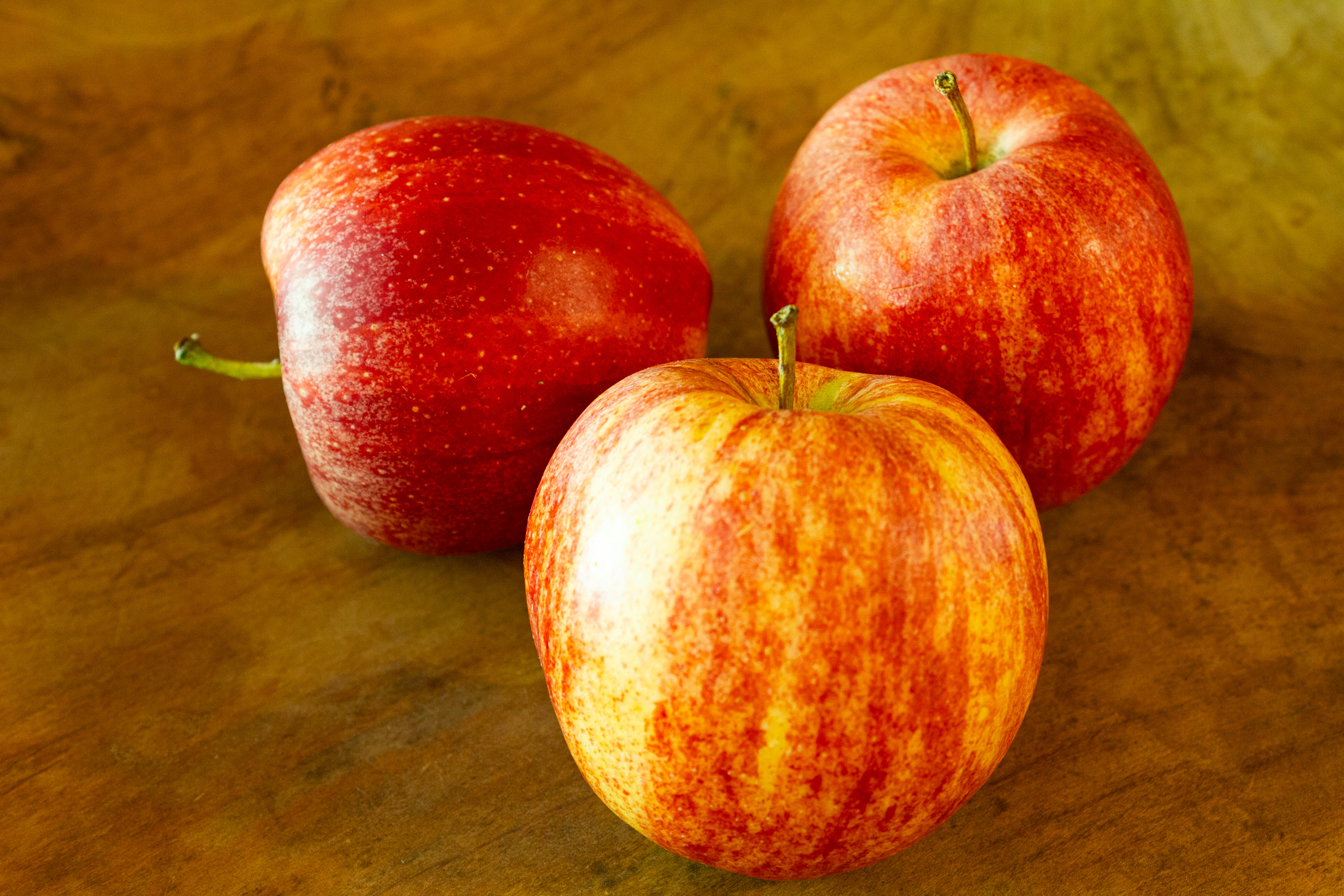 Drei rote Äpfel auf einer Holzfläche