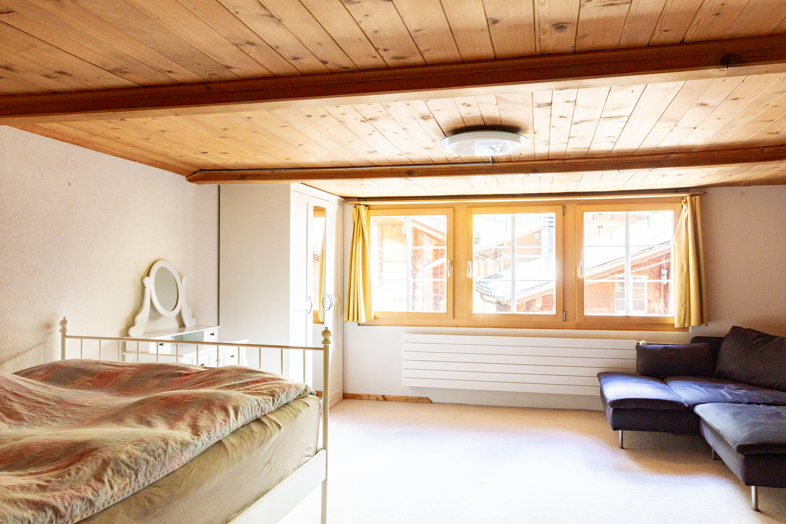 Gemütliches Dachzimmer mit Bett und Sofa