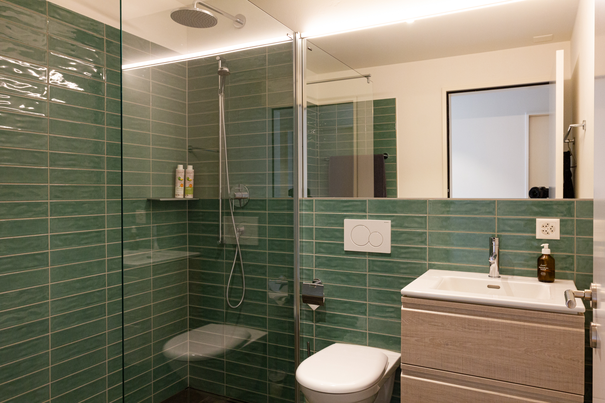 Modernes Badezimmer mit begehbarer Dusche und grünen Wandfliesen
