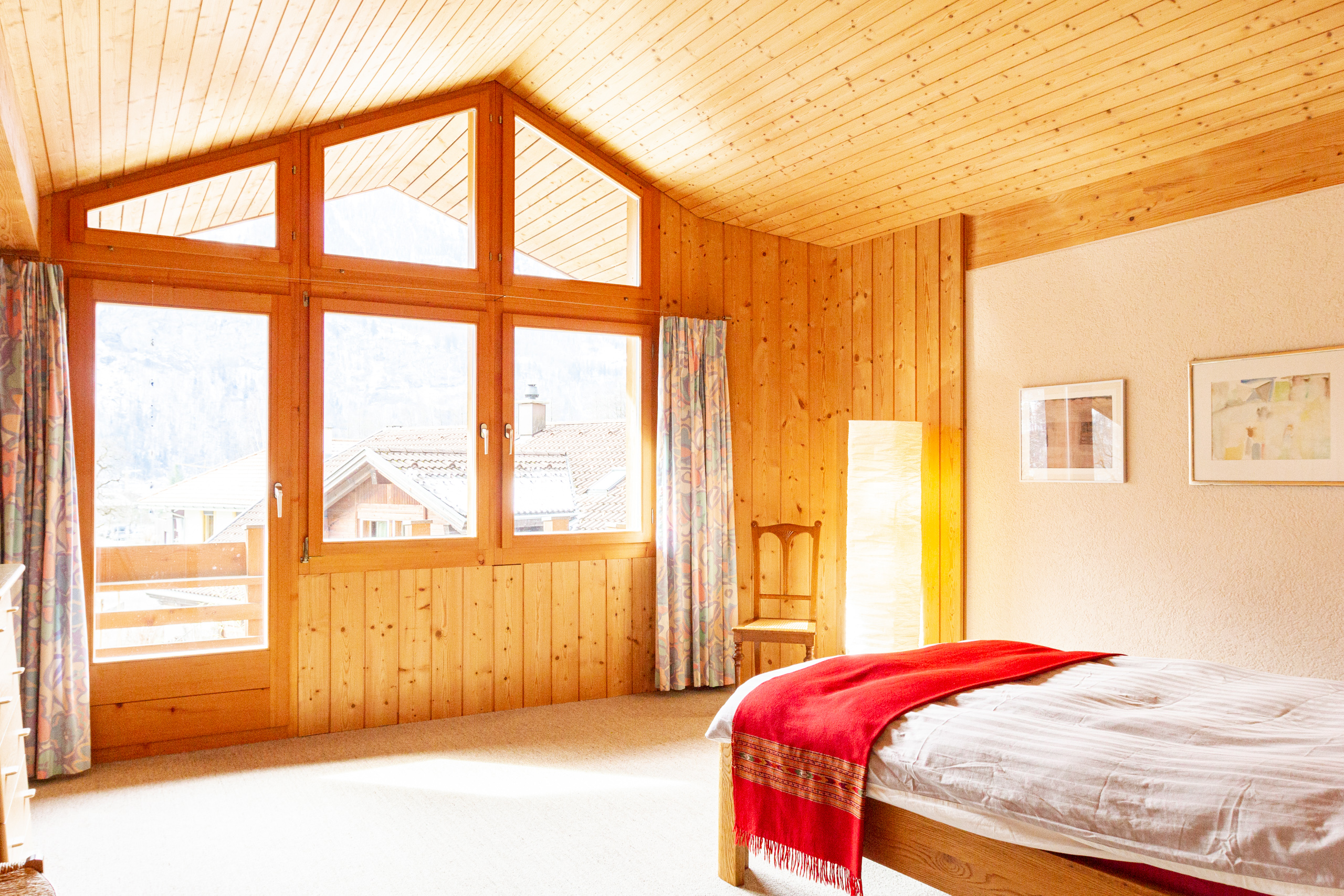 Helles Schlafzimmer mit Holzvertäfelung und großer Fensterfront