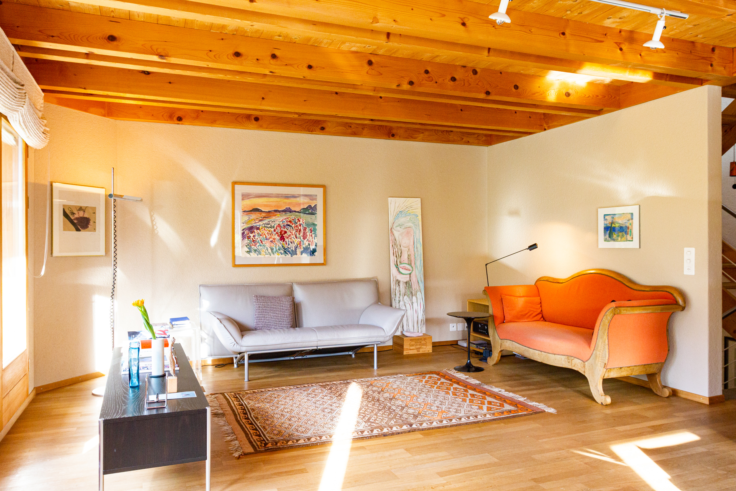 Heller Wohnraum mit Holzdecke und farbigen Sitzmöbeln