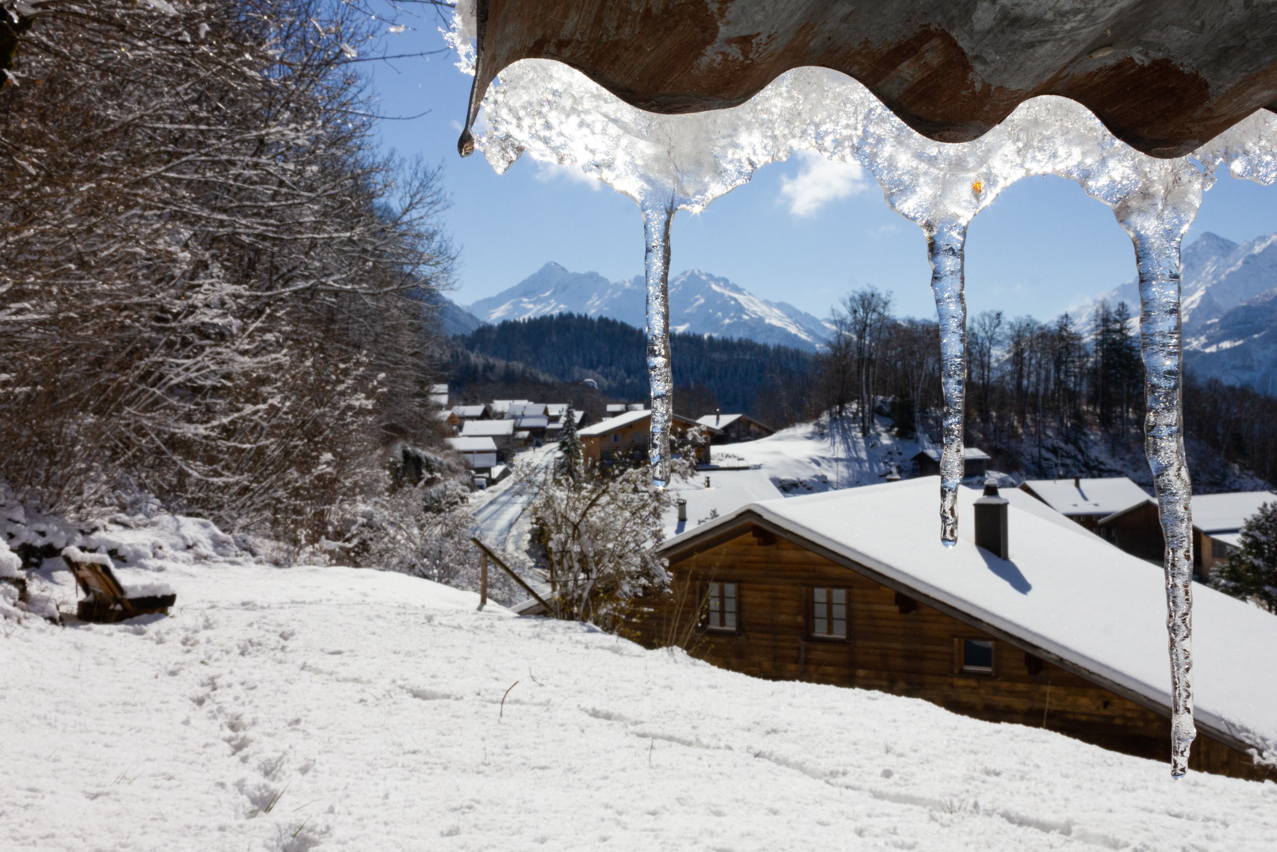 Winterliches Alpenpanorama mit vereisten Dachrinnen