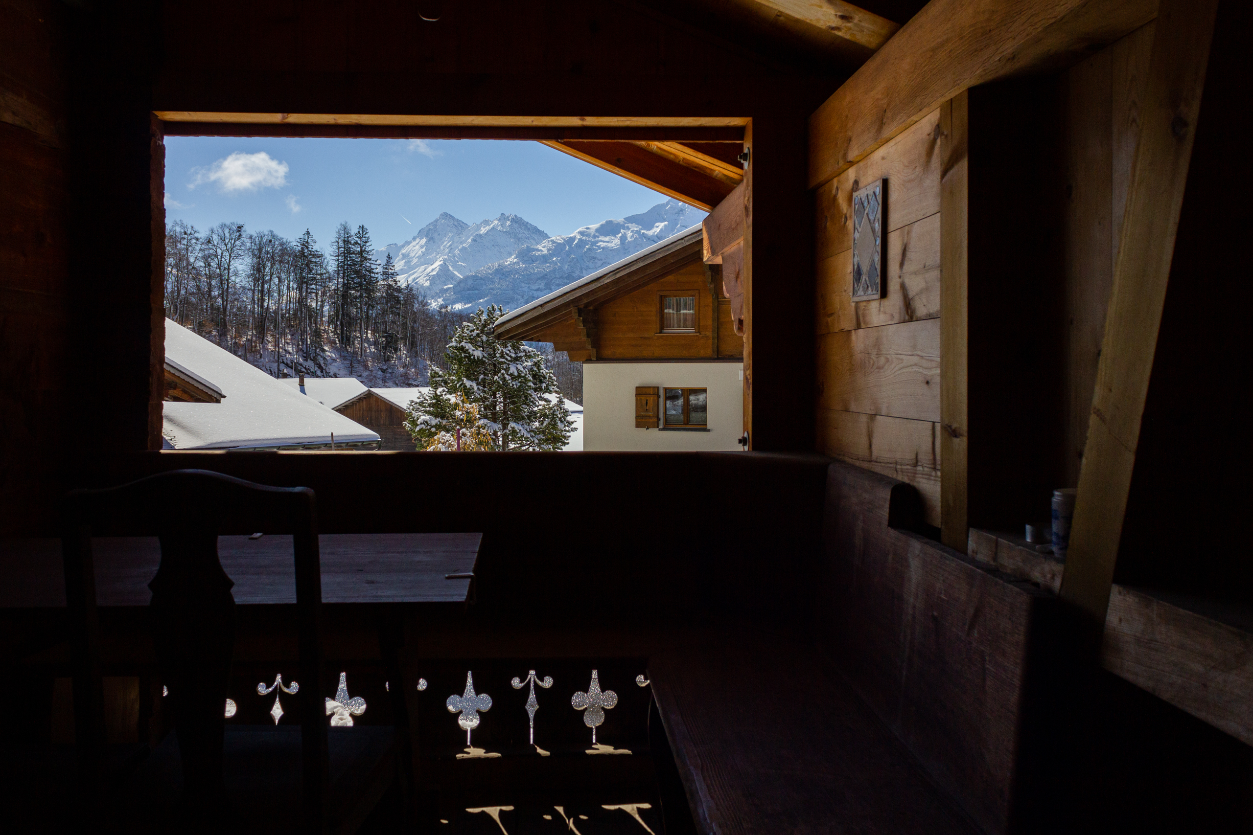 Blick aus einer rustikalen Holzhütte auf verschneite Berge