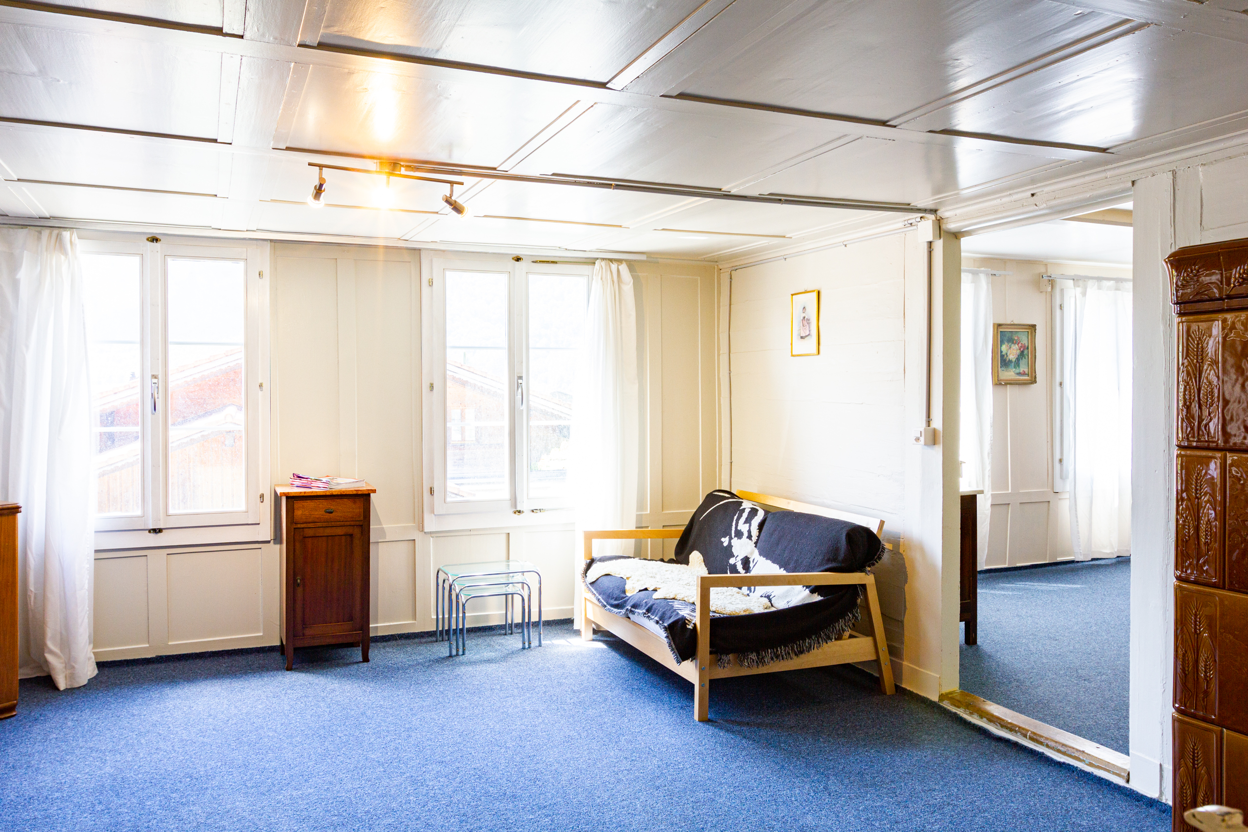Helles Zimmer mit blauer Teppichfläche und Sitzecke