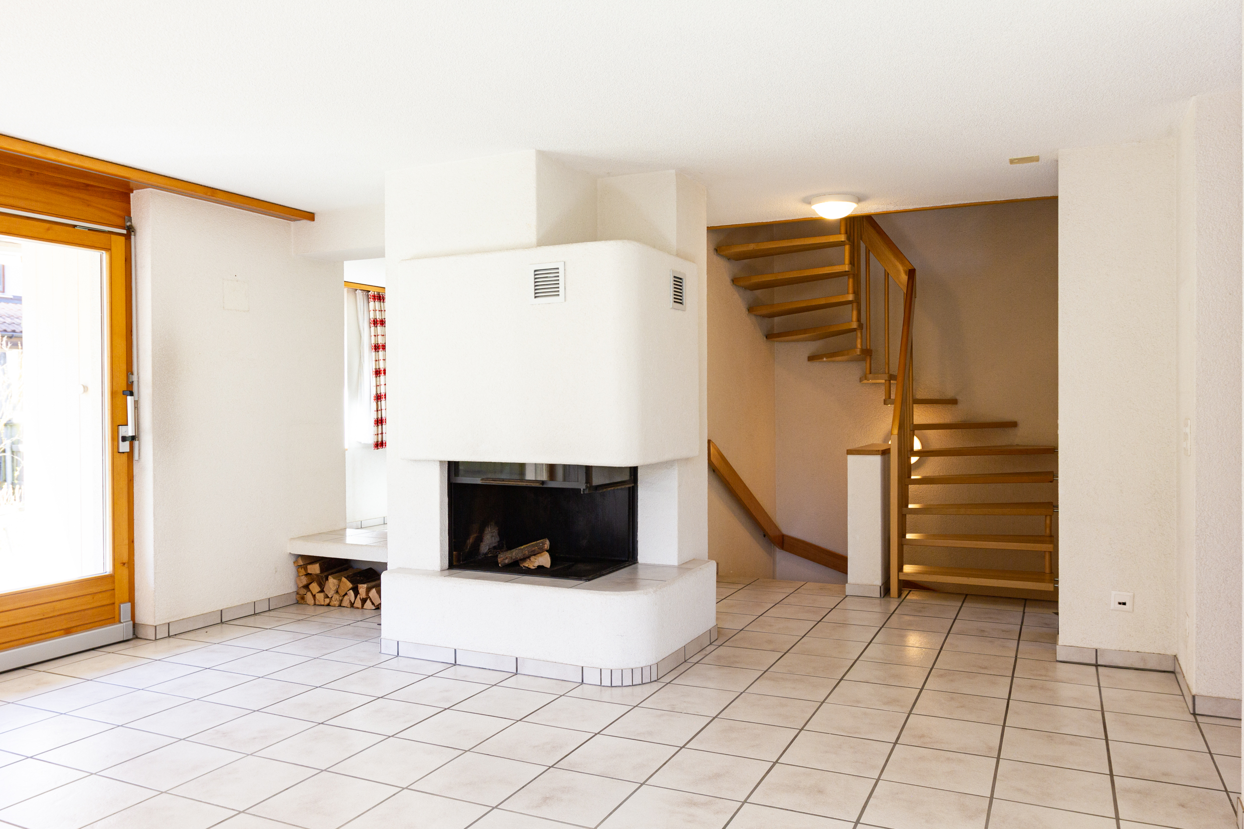 Wohnraum mit Kamin und Holztreppe