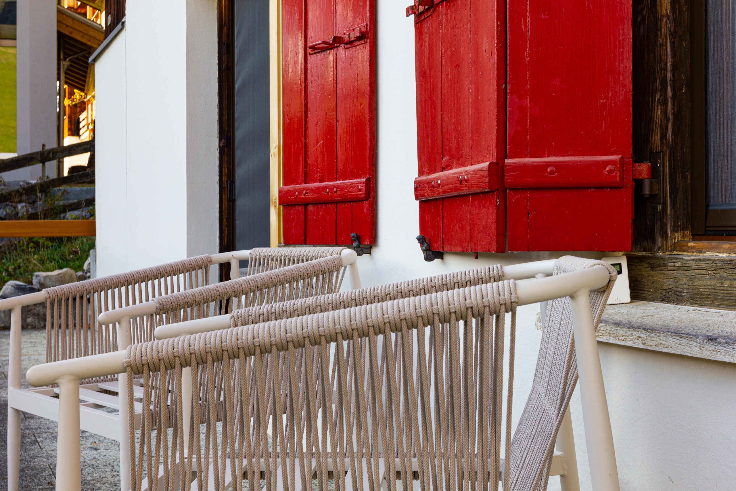 Außenansicht mit roten Fensterläden und Sitzmöbeln