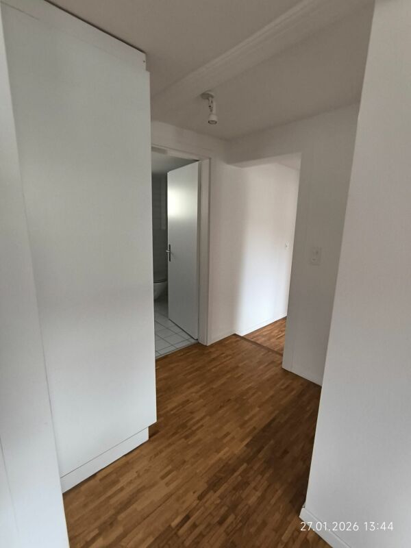 Flur mit Holzboden und offener Tür zum Bad