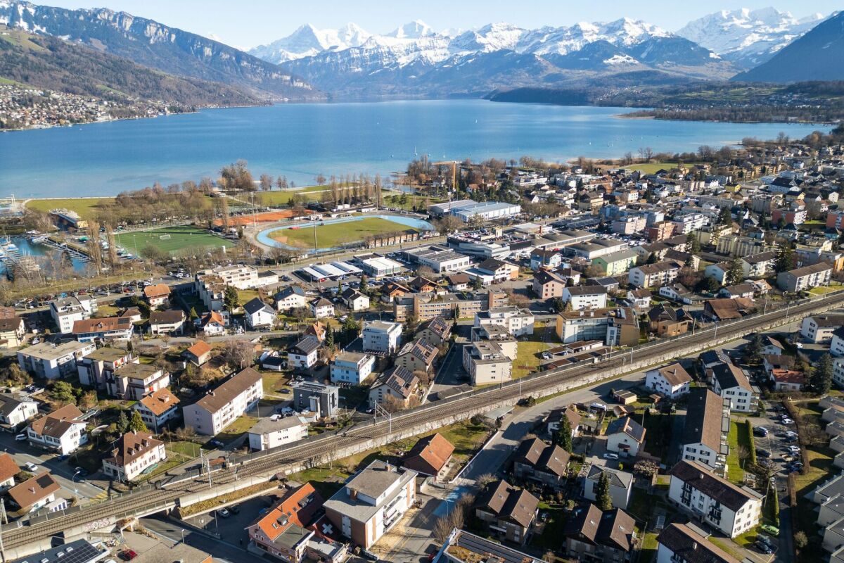 Luftaufnahme einer Stadt am See mit Alpenpanorama