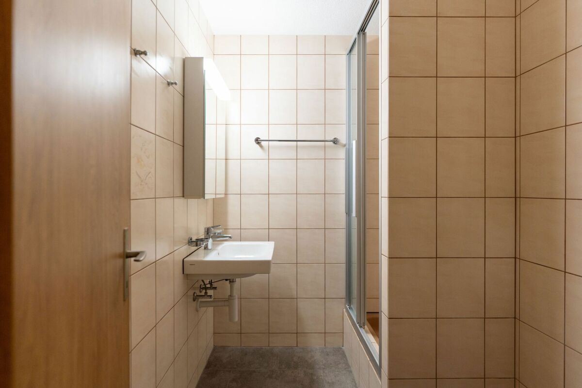 Schmales Badezimmer mit Dusche und Waschtisch