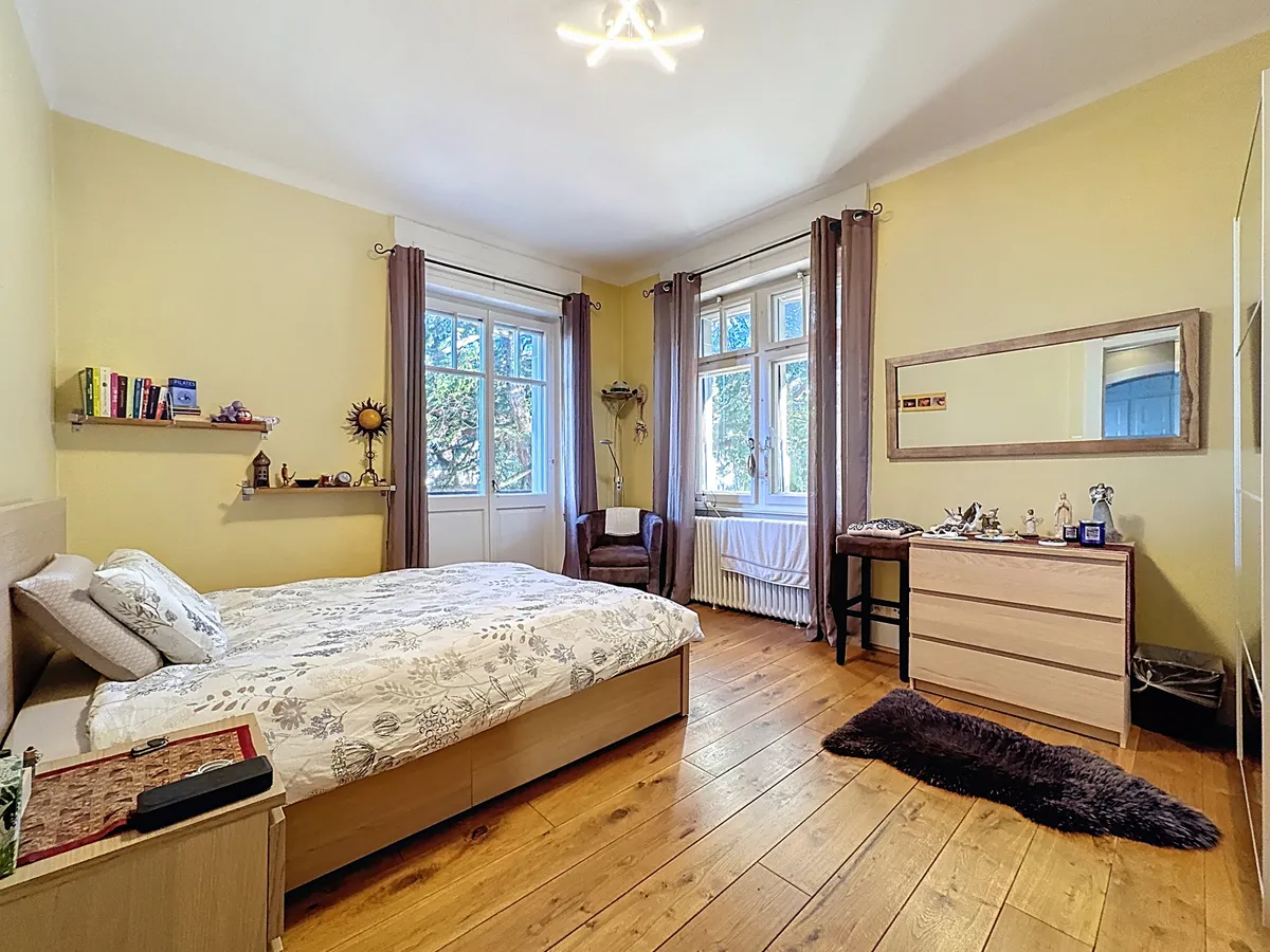 Helles Schlafzimmer mit Holzboden und zwei Fenstern