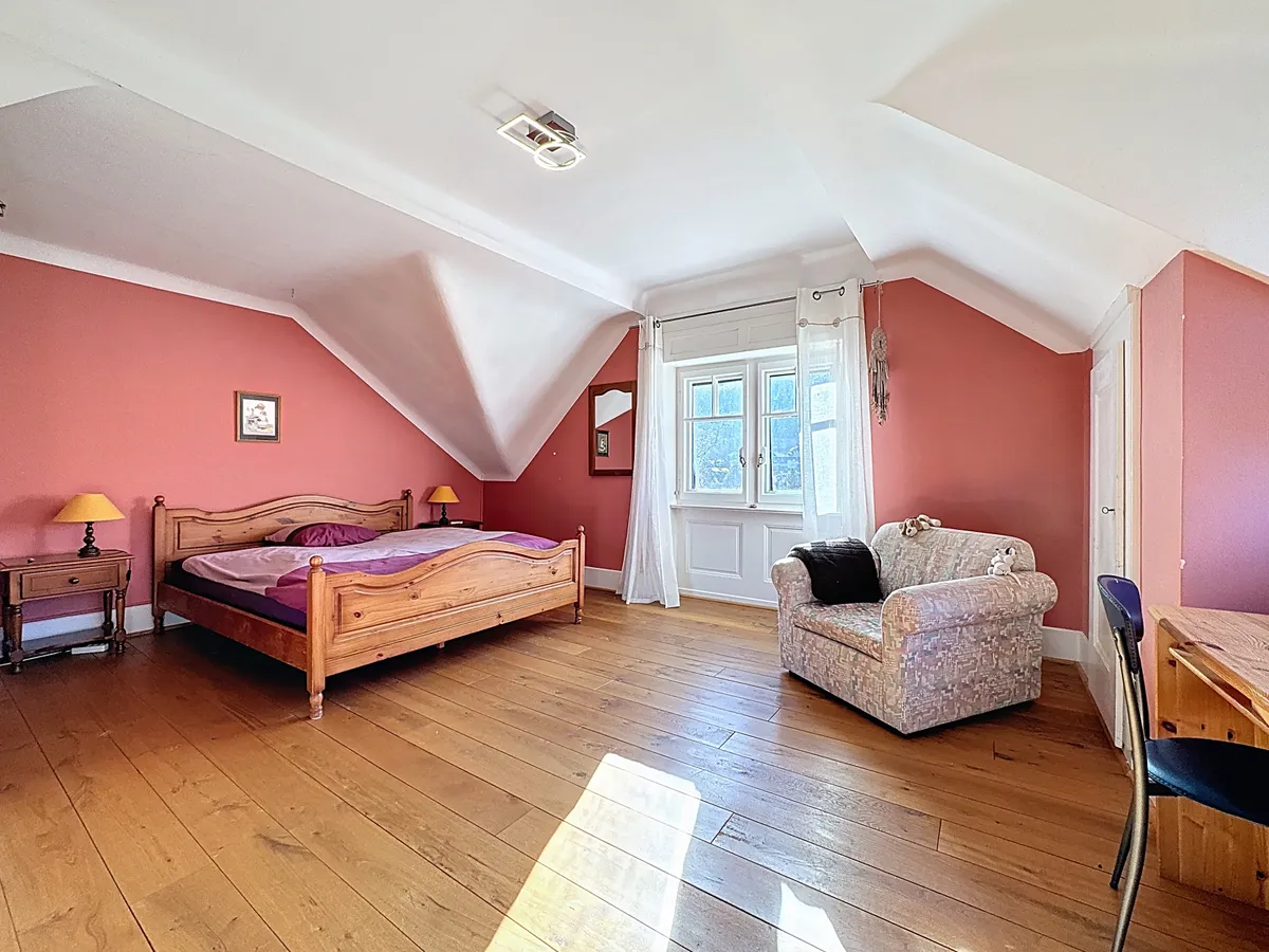 Dachzimmer mit Holzbett und Sitzbereich
