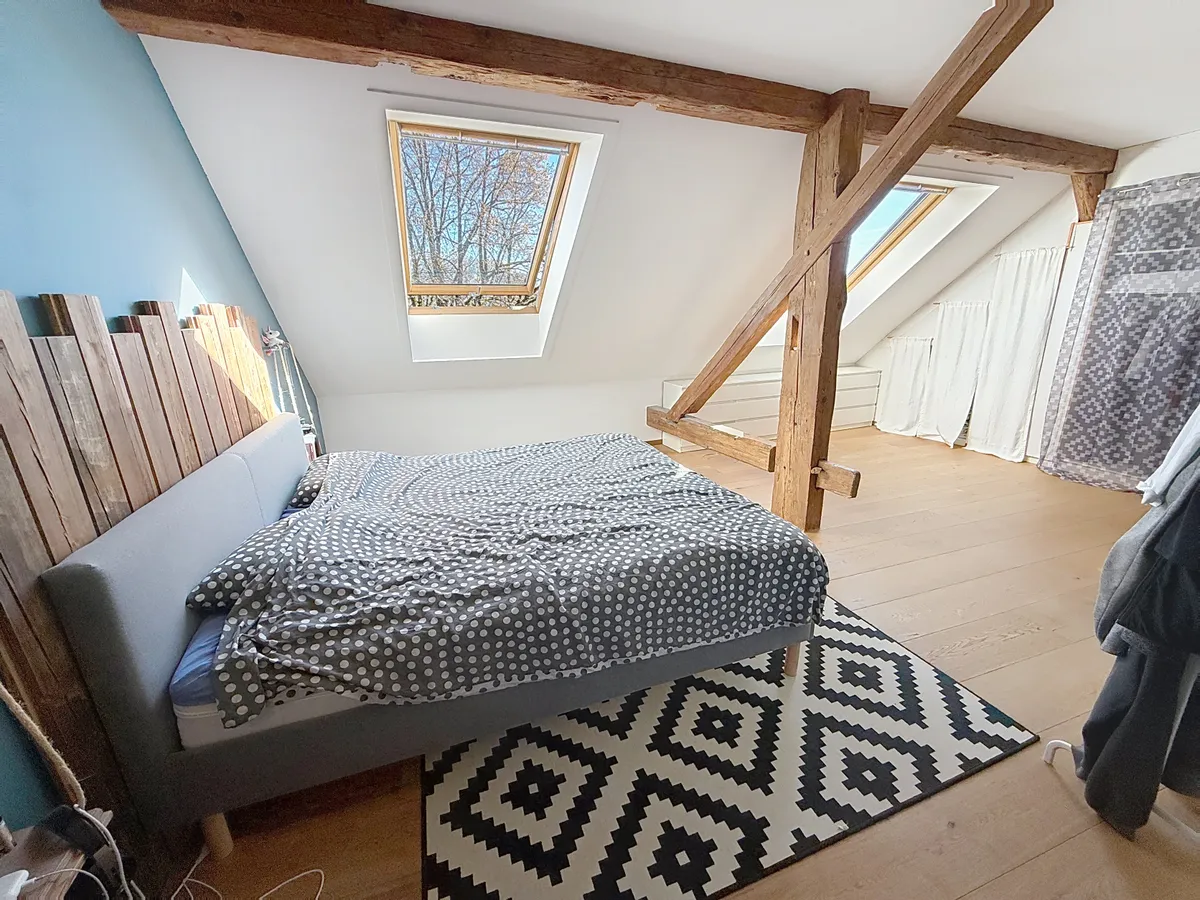 Dachgeschoss-Schlafzimmer mit sichtbaren Holzbalken