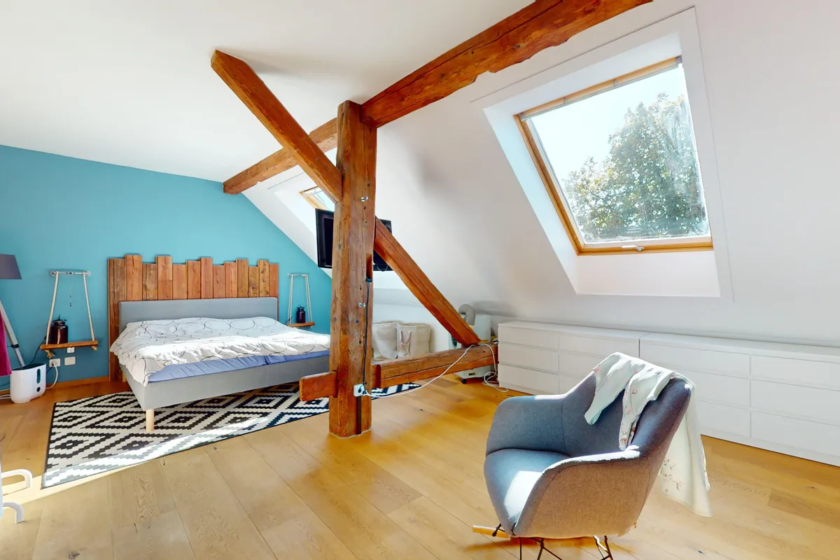 Dachgeschoss-Schlafzimmer mit sichtbaren Holzbalken