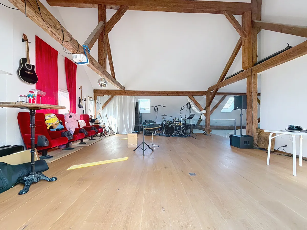 Großer Dachraum mit sichtbaren Holzbalken und Musikbereich