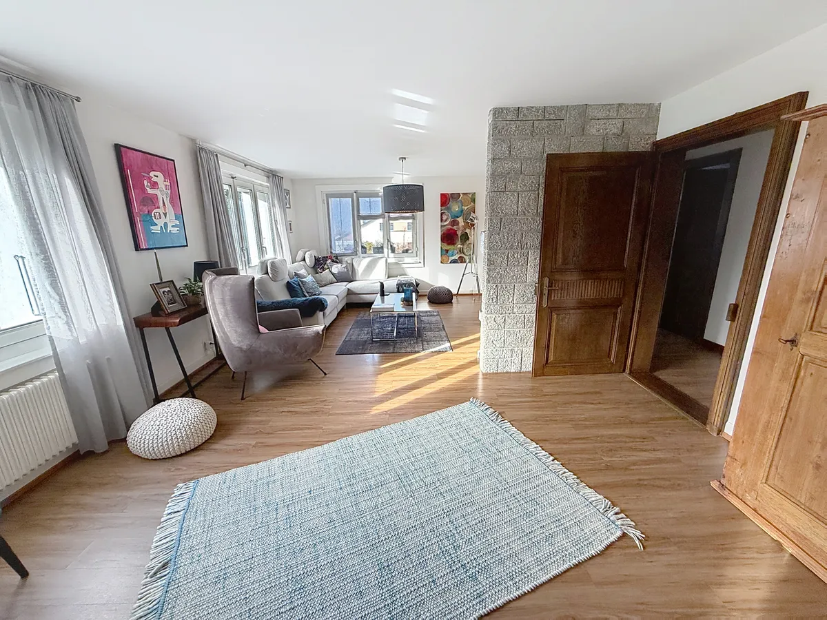 Helles Wohnzimmer mit Holzoptikboden und Sitzgruppe