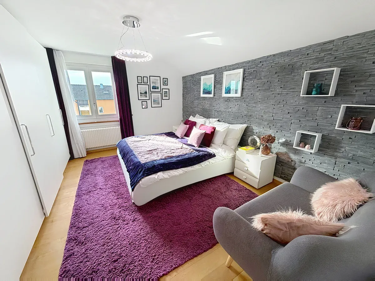 Modernes Schlafzimmer mit violettem Teppich und Akzentwand