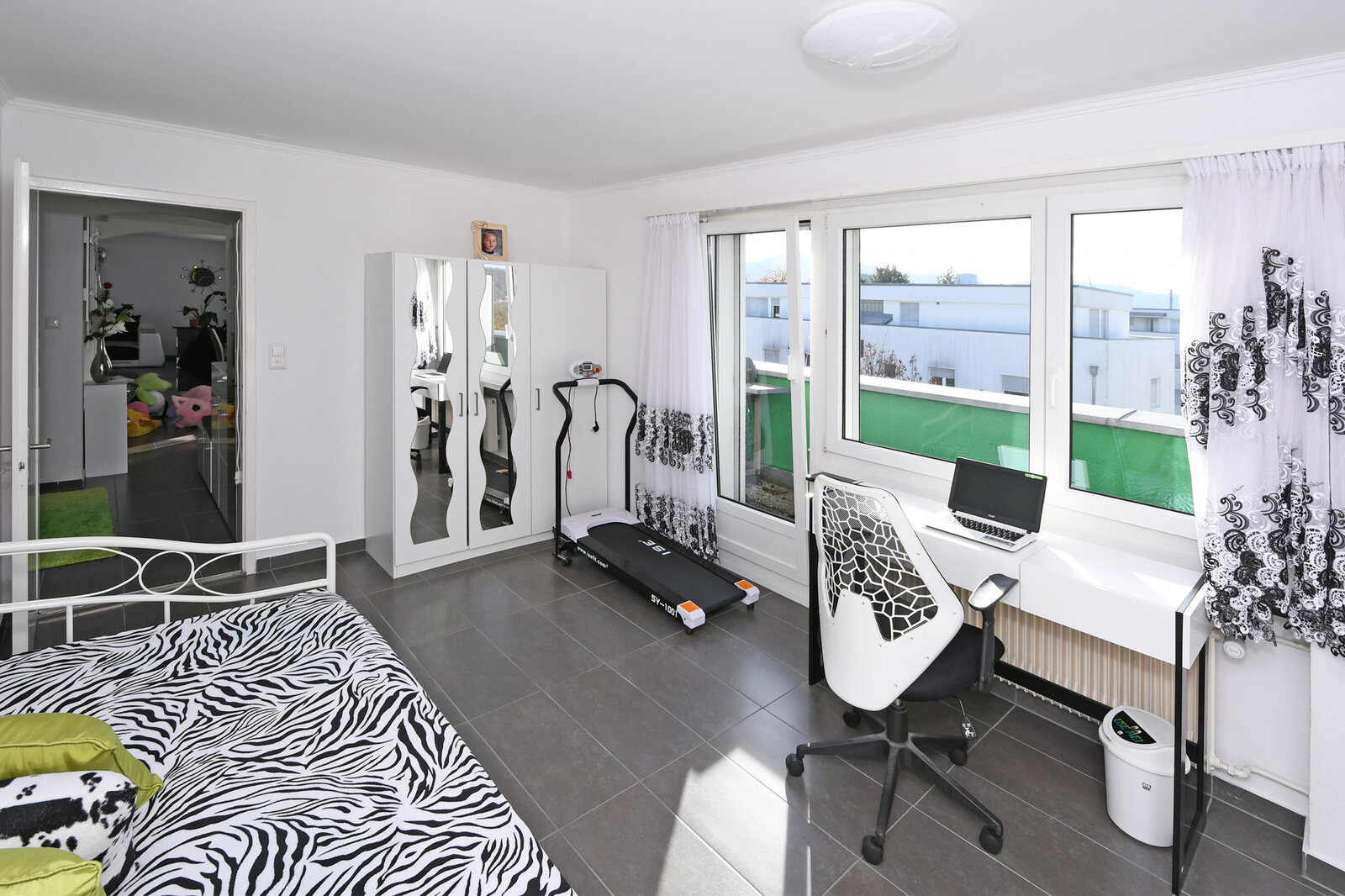 Helles Schlafzimmer mit Arbeitsplatz und Balkonblick