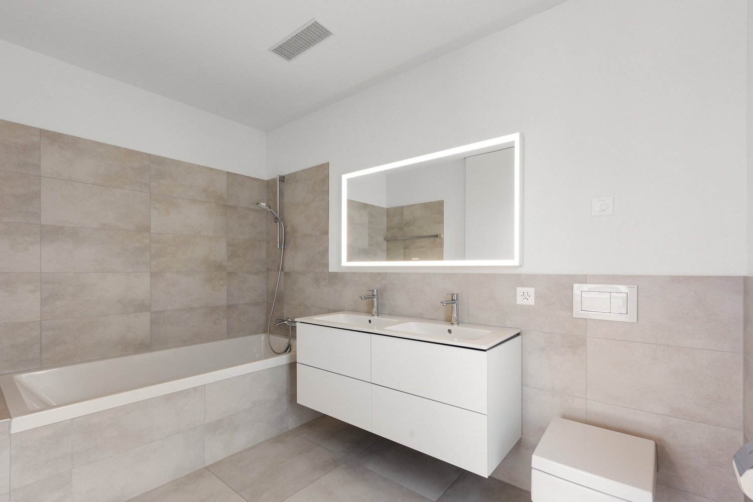 Modernes Badezimmer mit Wanne und beleuchtetem Spiegelschrank