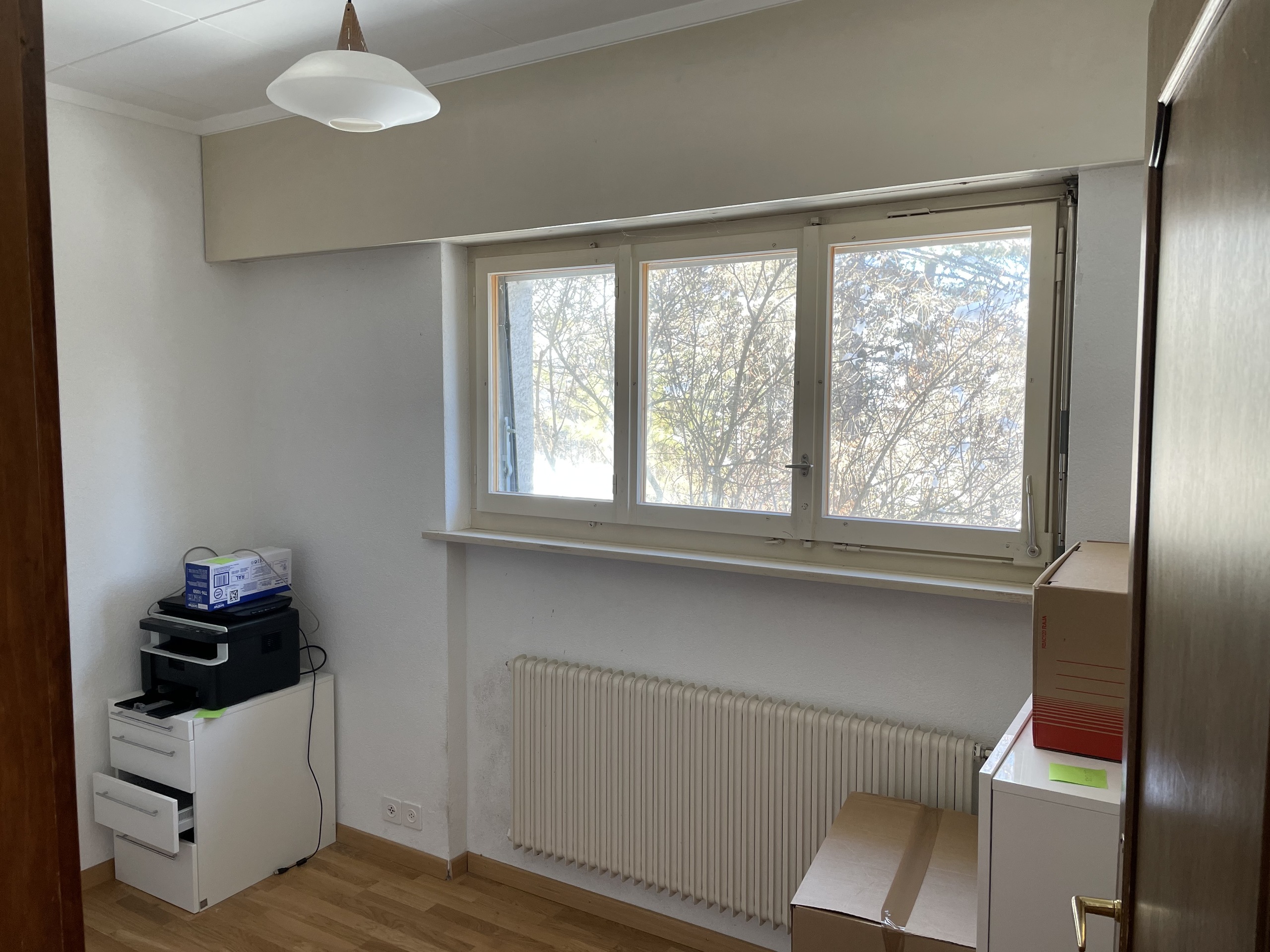 Helles kleines Zimmer mit Fenster, Heizkörper und wenigen Möbeln