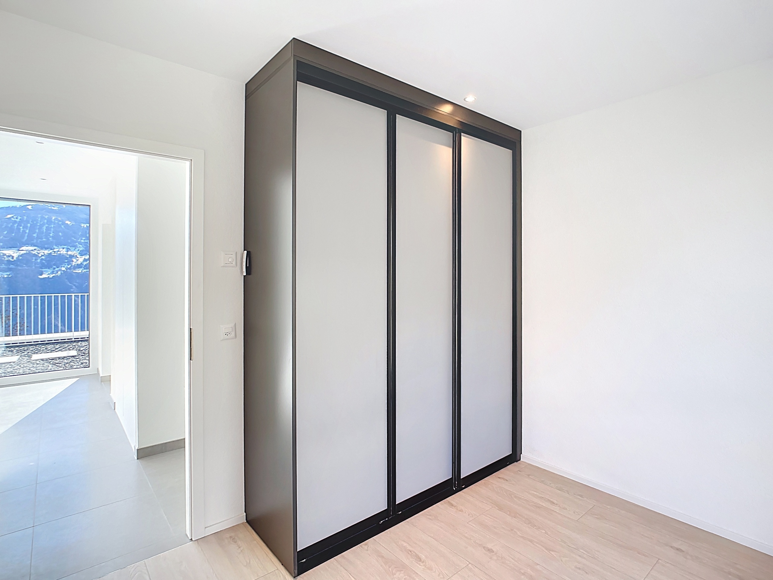 Modernes Schlafzimmer mit Einbauschrank und Blick ins Freie