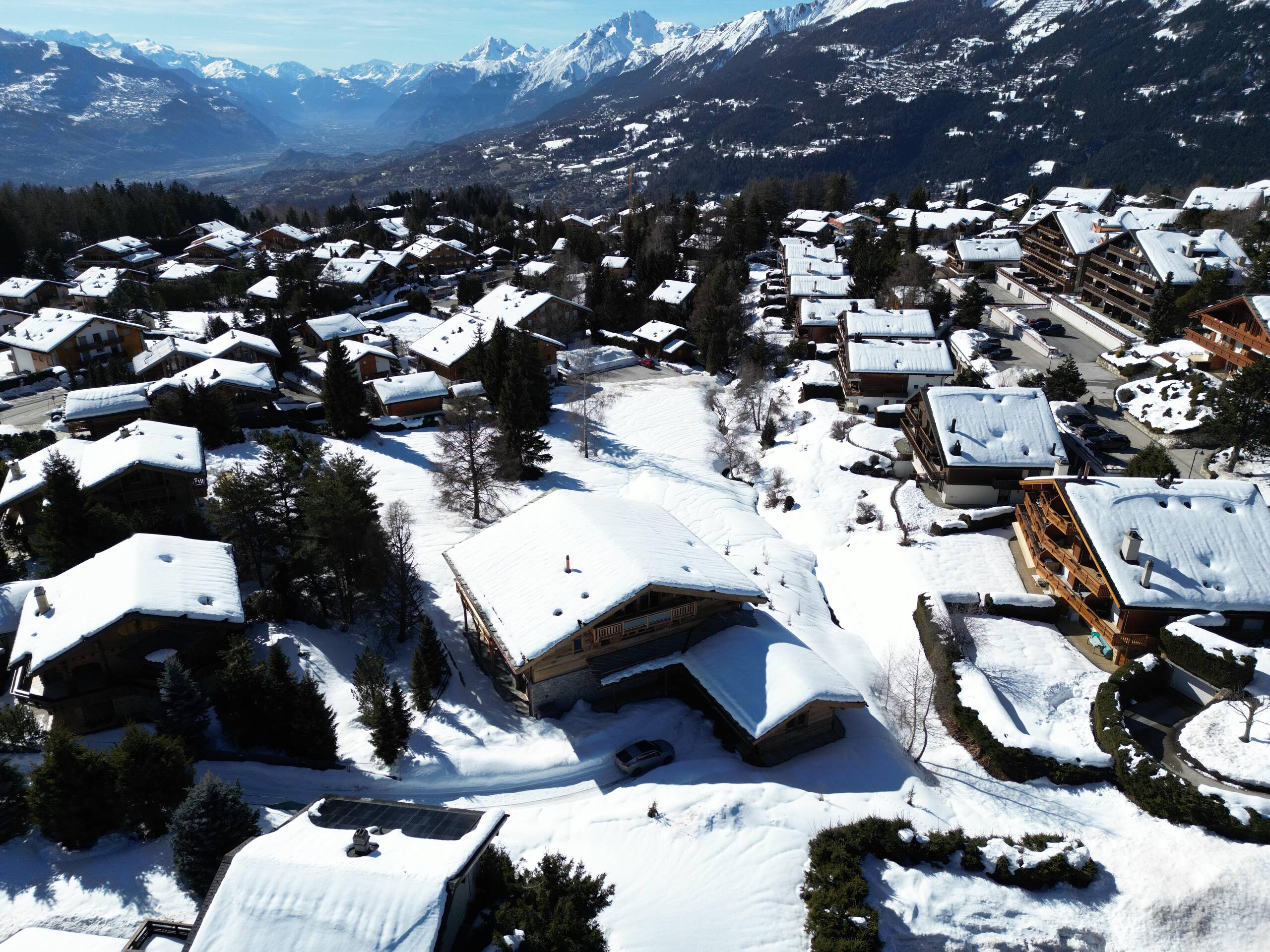 Schneebedeckte Alpen-Siedlung mit Talblick