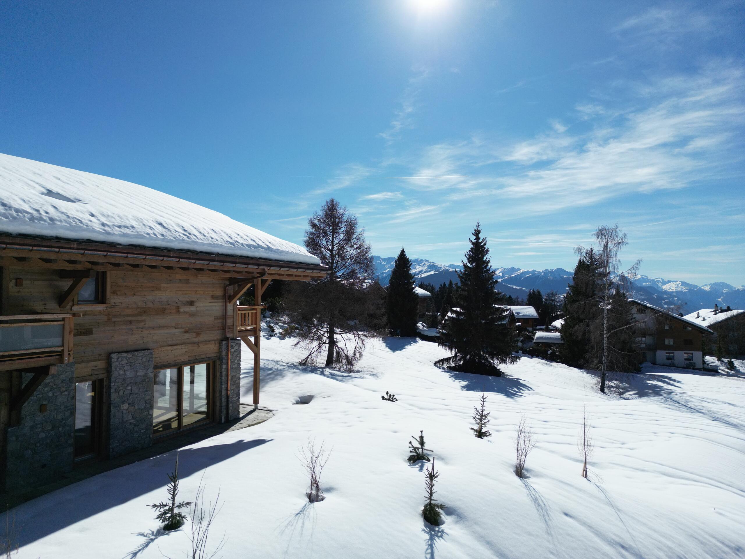 Alpine-Haus mit verschneitem Hang und Bergblick