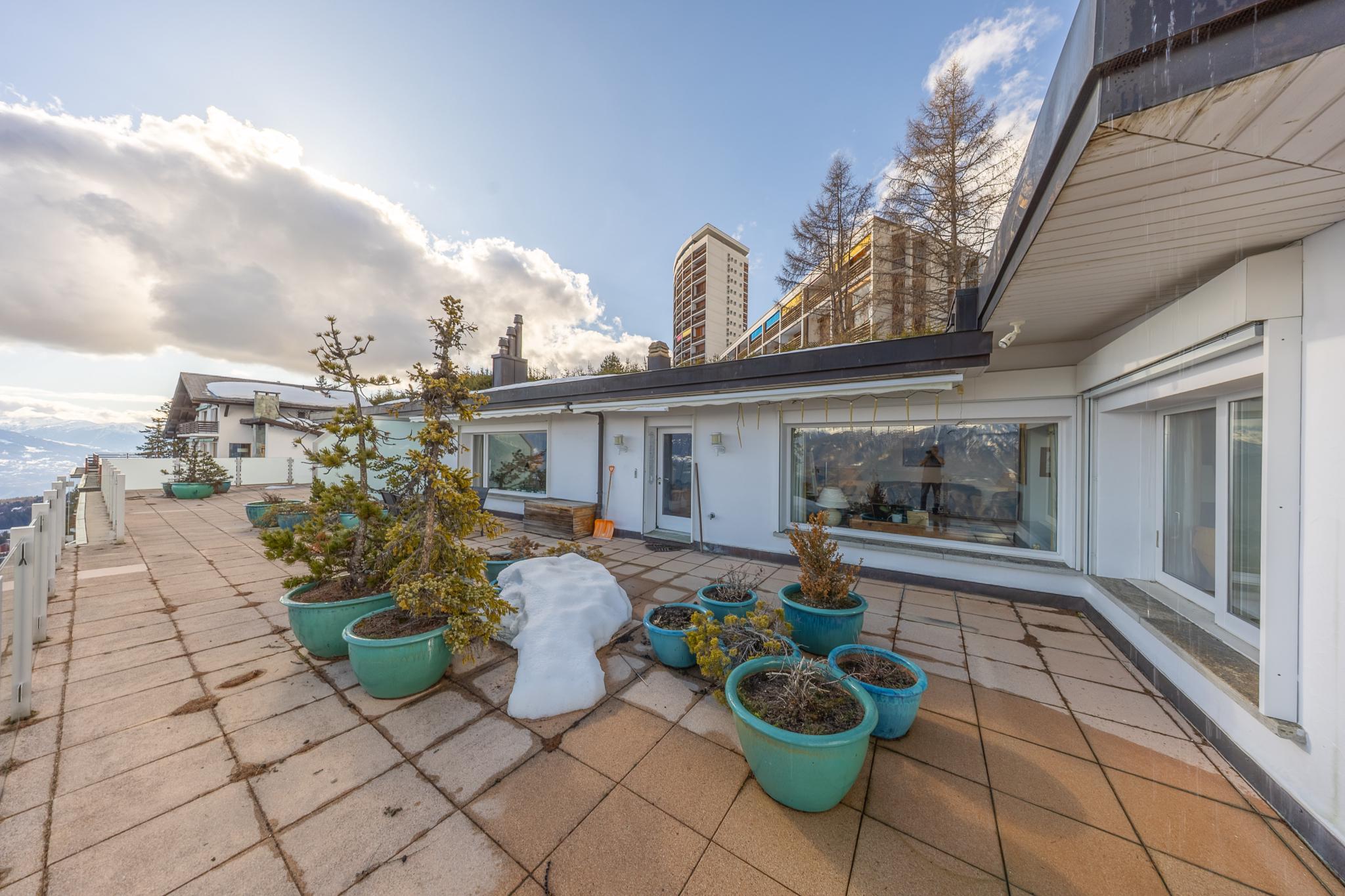 Große Dachterrasse mit Pflanzkübeln und Bergblick