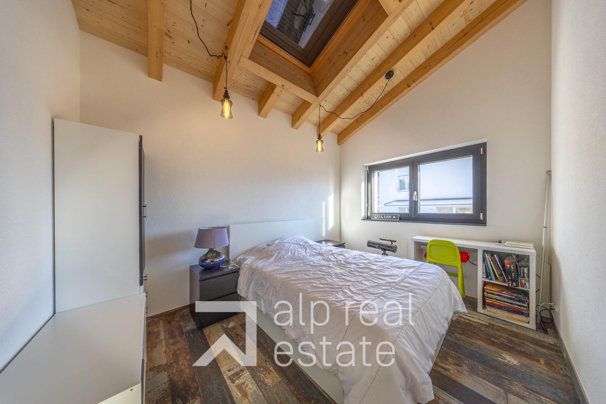 Dachgeschoss-Schlafzimmer mit sichtbaren Holzbalken