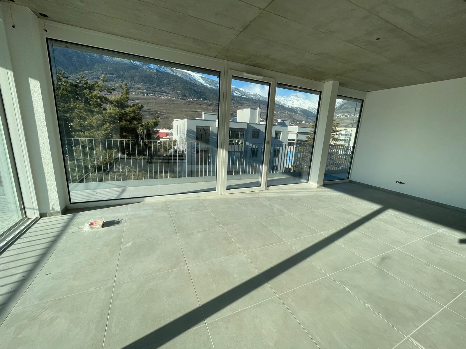 Heller leerer Wohnraum mit Panoramafenstern und Bergblick
