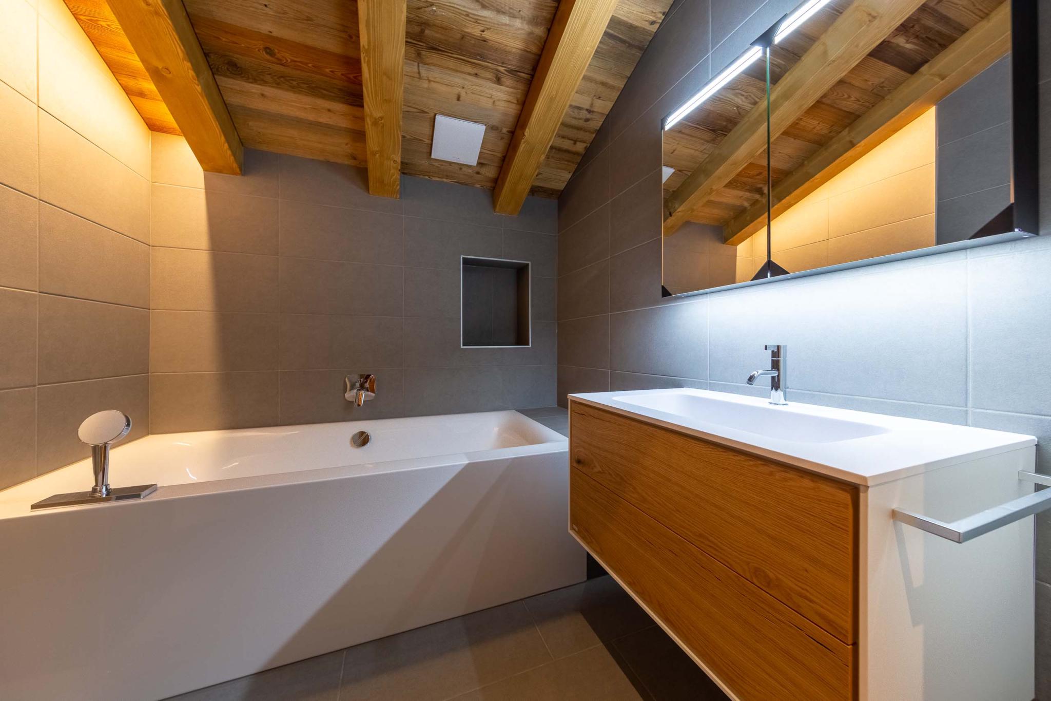 Modernes Badezimmer mit Badewanne und Waschtisch unter Holzbalken