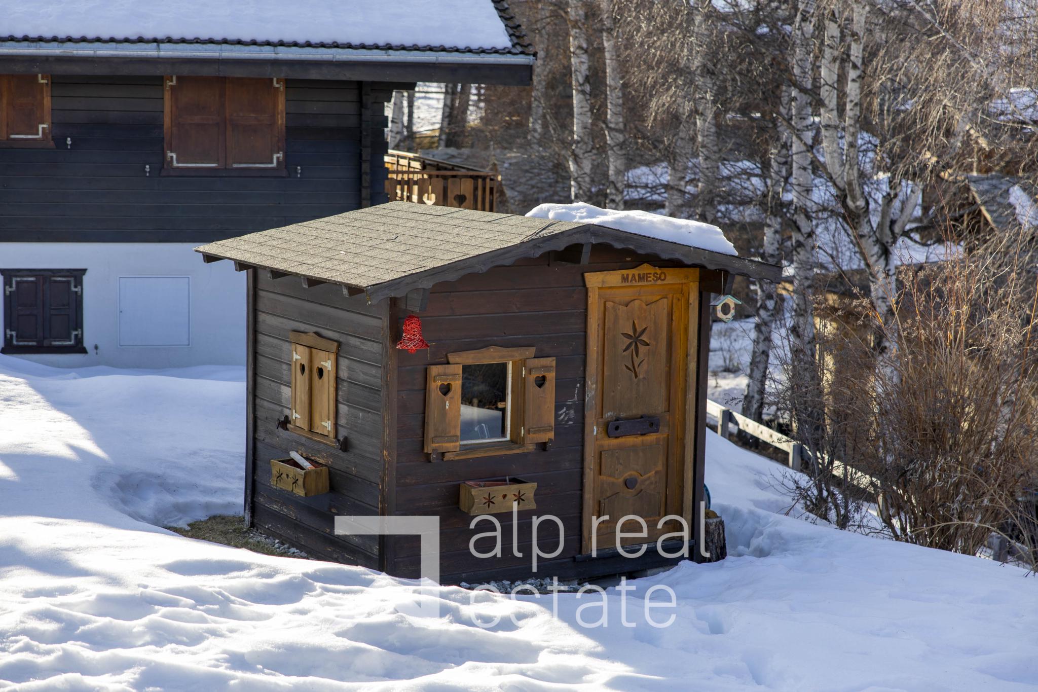 Holzhütte im Schnee vor einem Wohnhaus