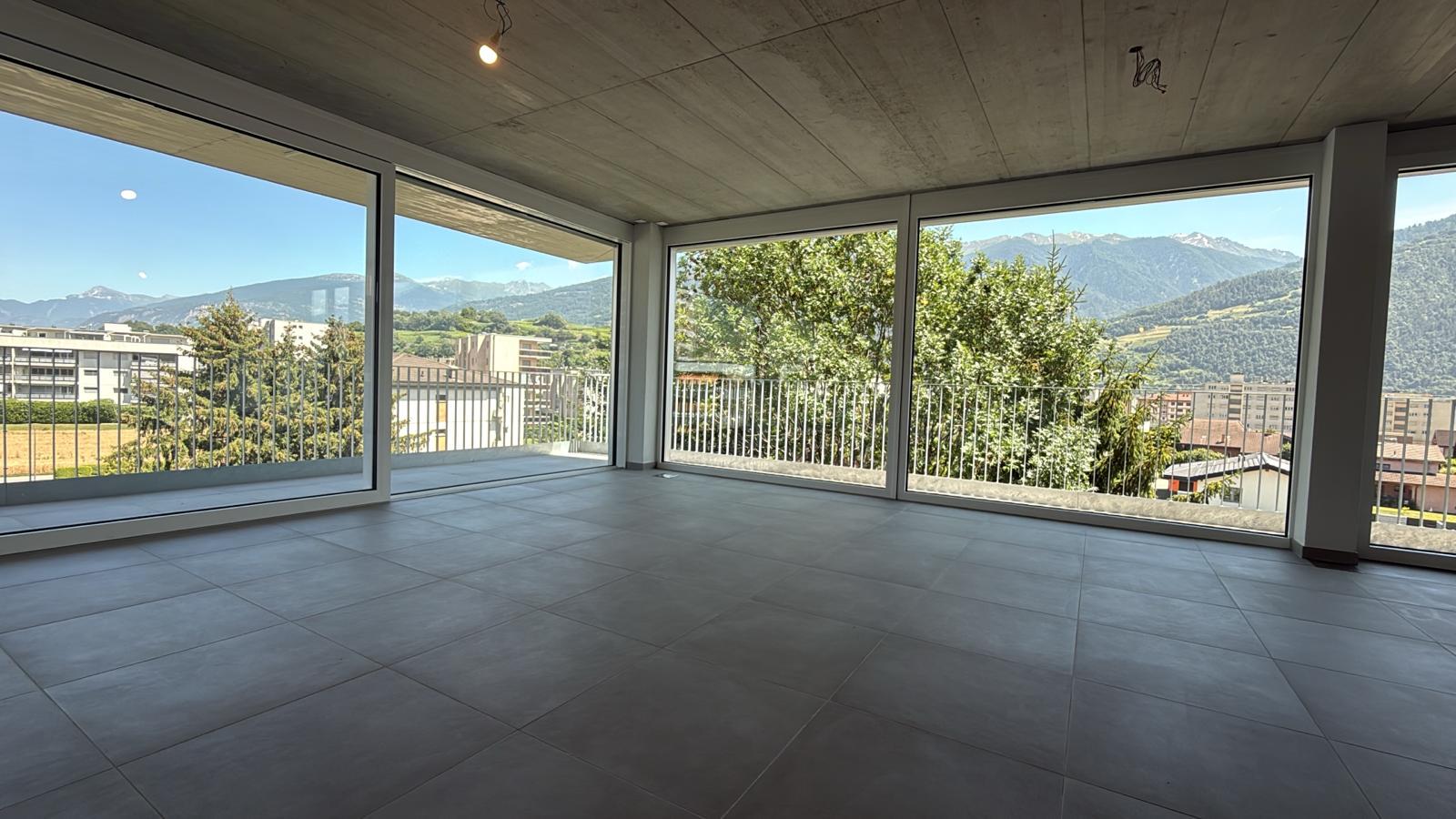 Großer leerer Wohnraum mit Panoramafenstern und Bergblick