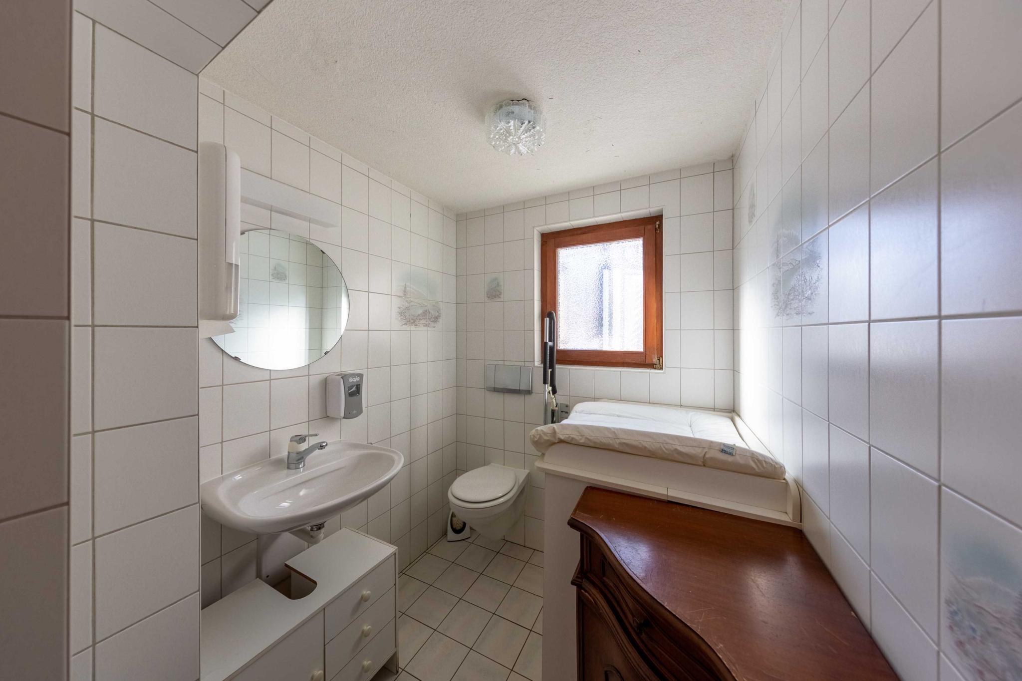 Kleines gefliestes Bad mit Waschbecken, WC und Fenster