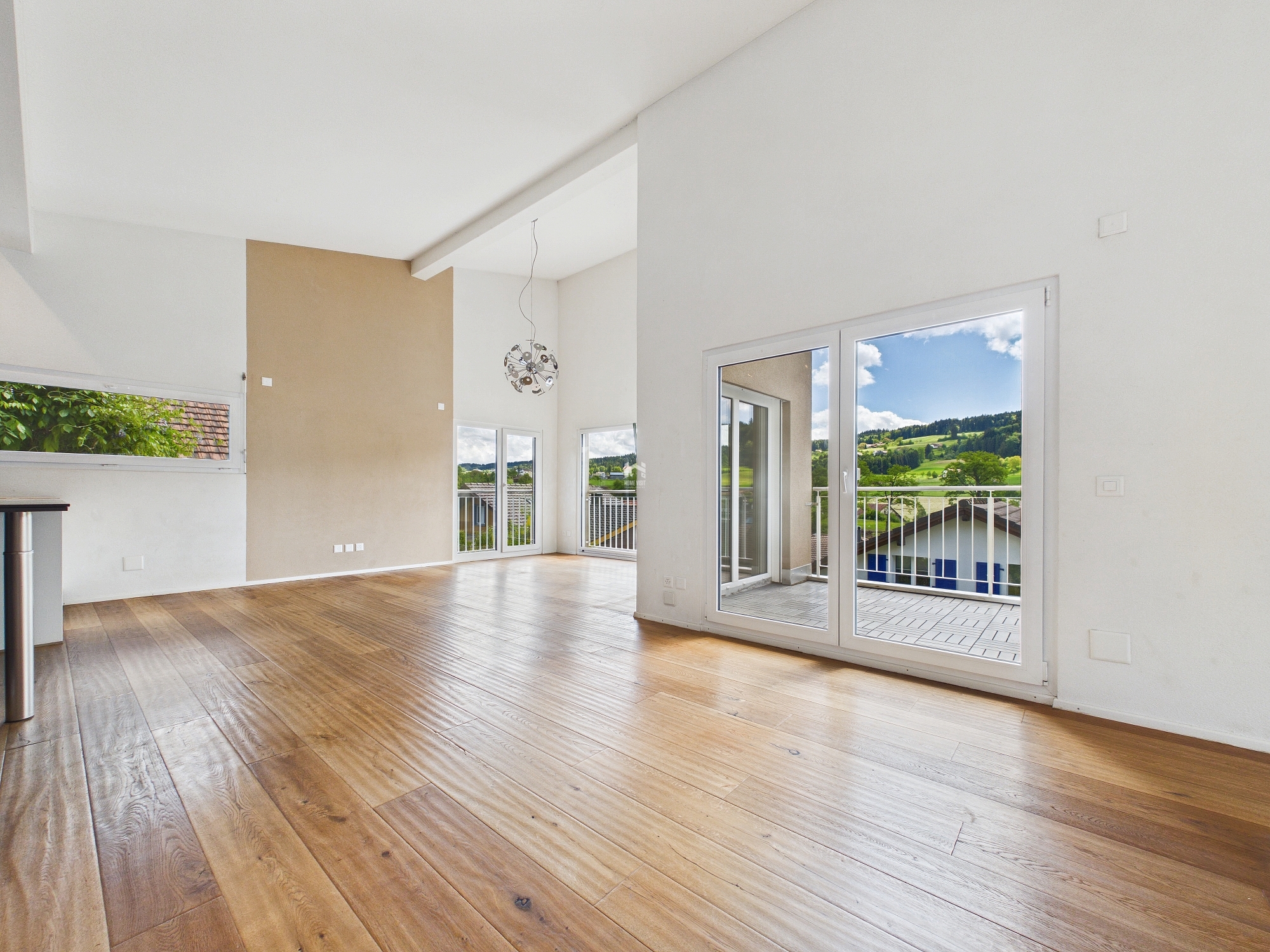 Heller Wohnraum mit großer Fensterfront und Balkonzugang