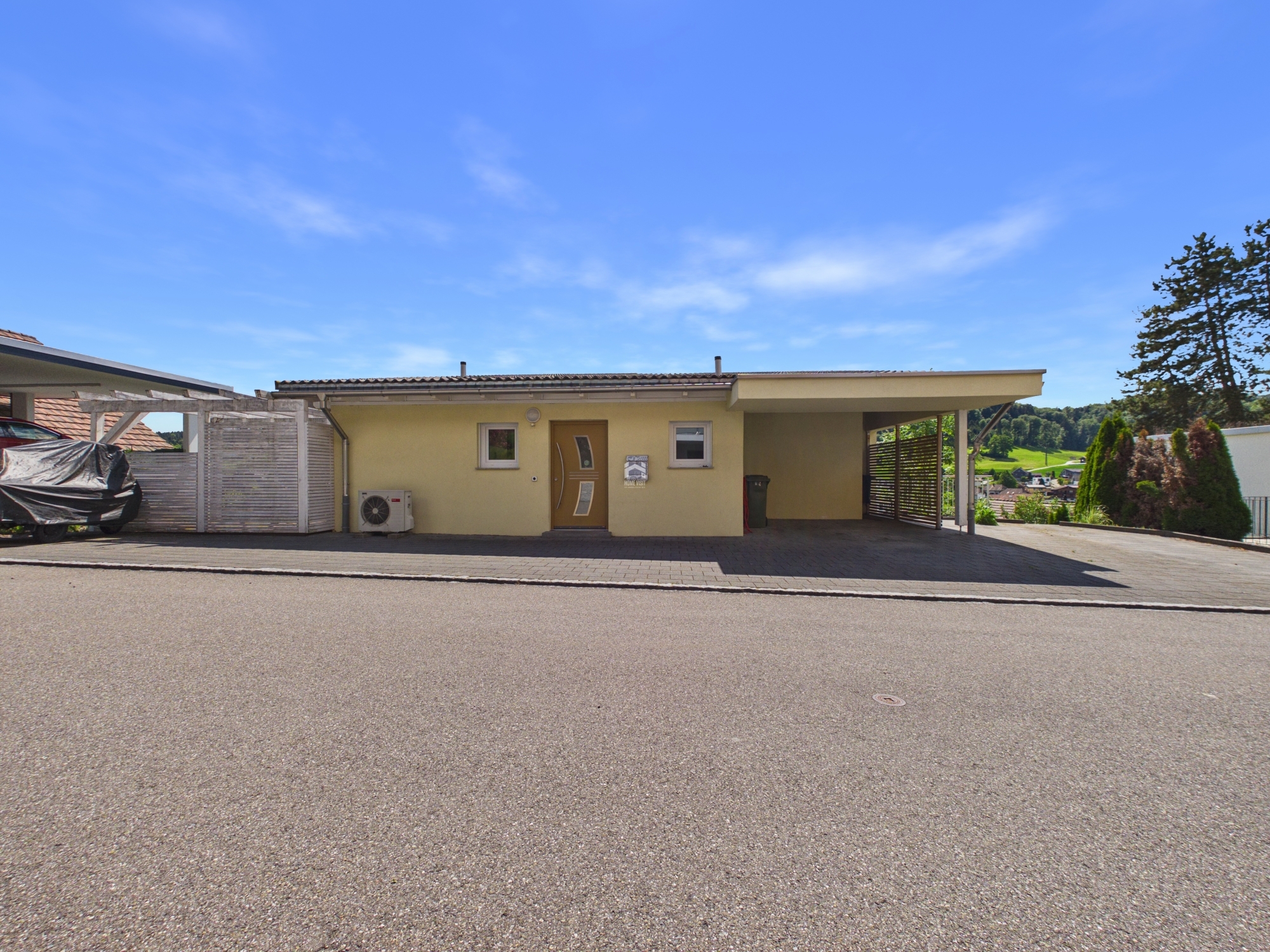Außenansicht eines eingeschossigen Hauses mit Carport und Zufahrt