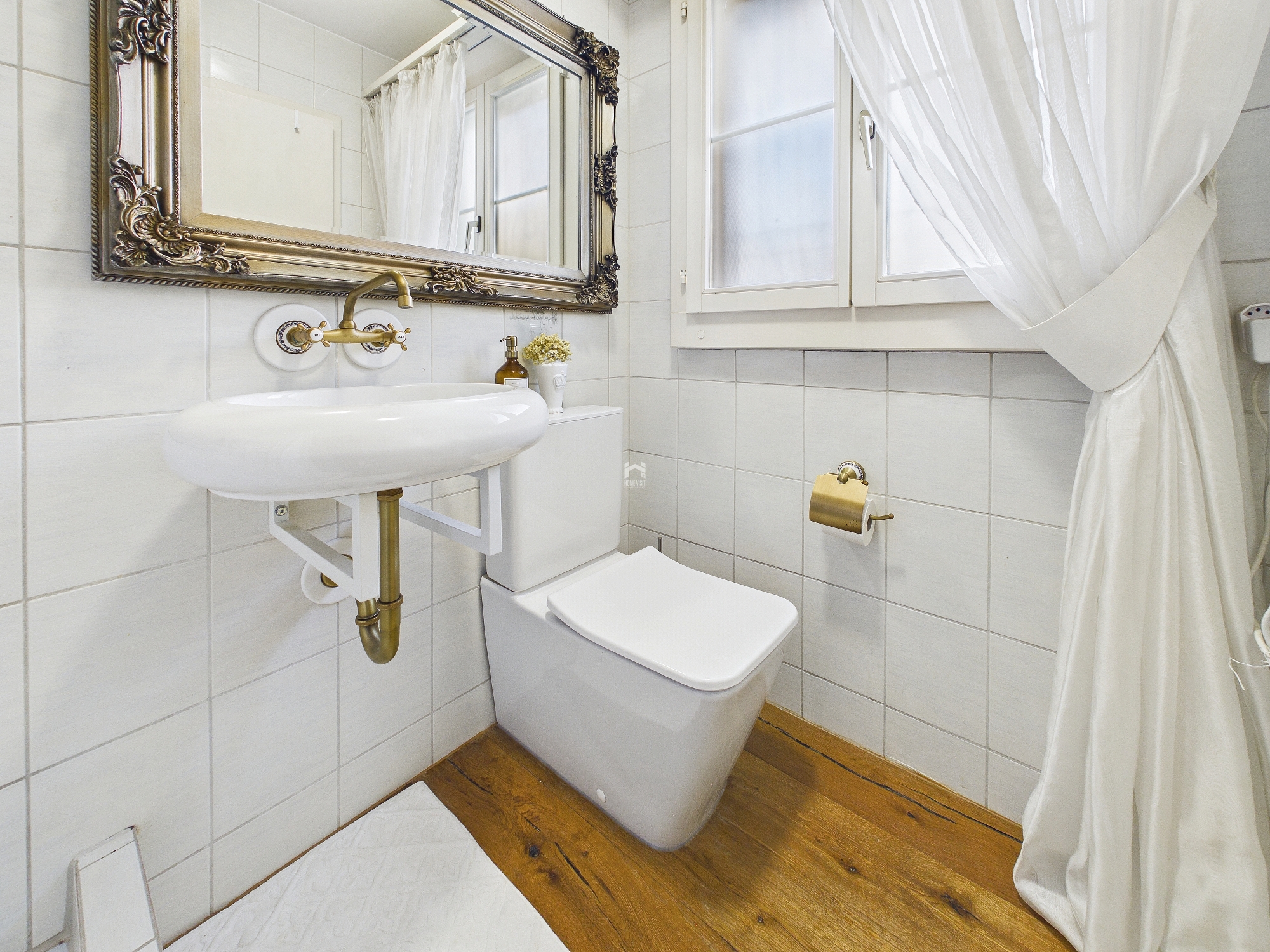 Kleines, helles Gäste-WC mit klassischem Waschtisch und goldenen Armaturen