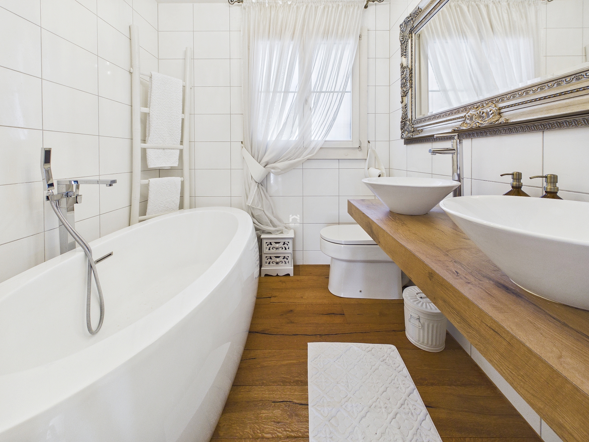 Kleines, elegant gestaltetes Badezimmer mit freistehender Badewanne und Doppelwaschtisch.