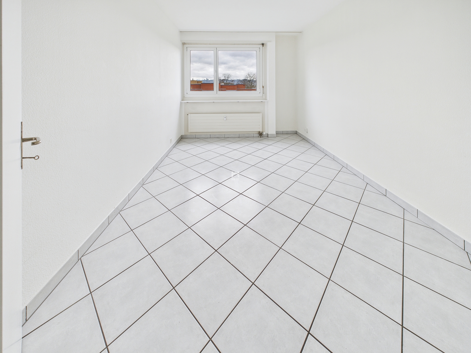 Leerer heller Raum mit Fliesenboden und Fenster