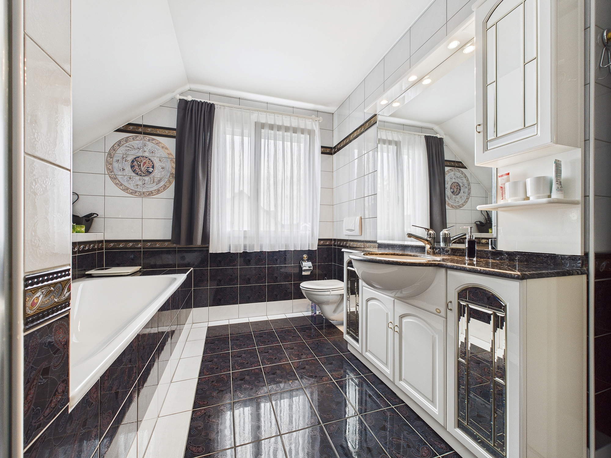 Elegantes Badezimmer mit dunklen Fliesen und Dachschräge