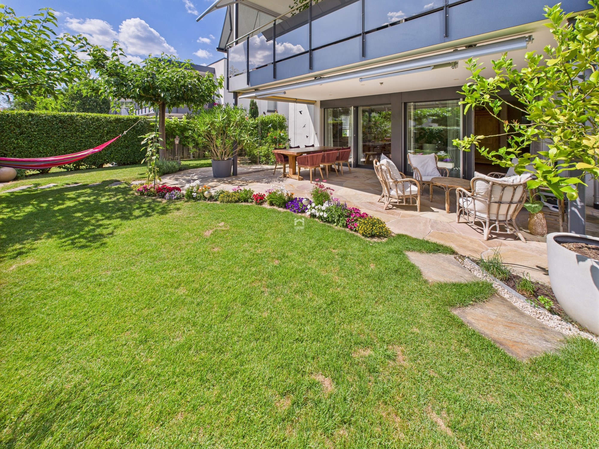 Garten mit Terrasse und Hausfassade
