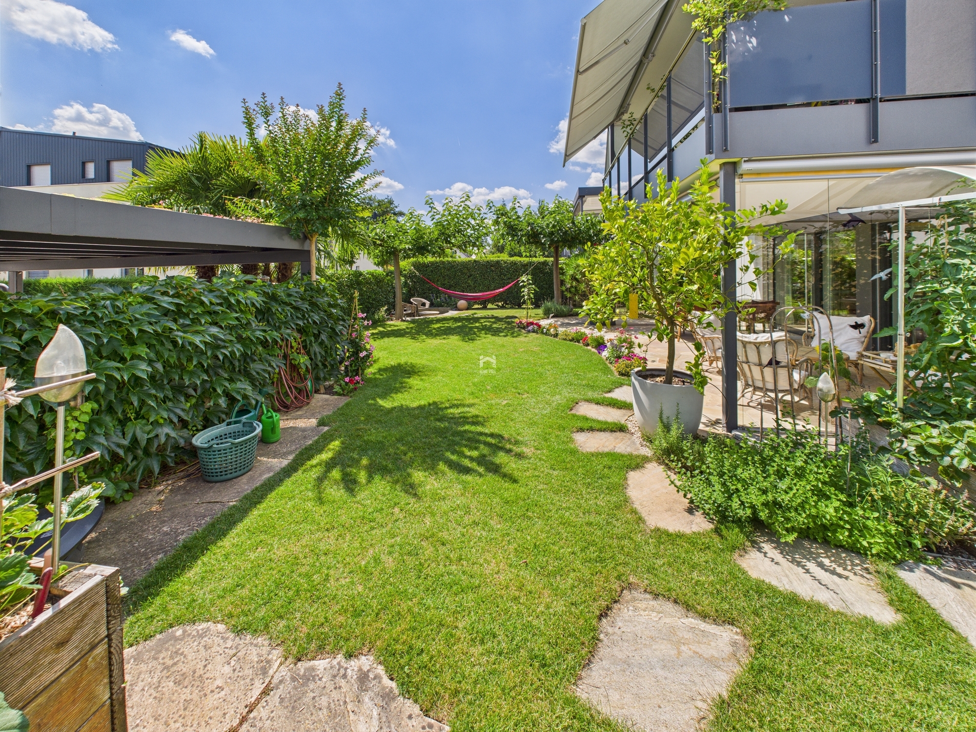 Großer, sonniger Garten mit Terrasse und moderner Hausansicht