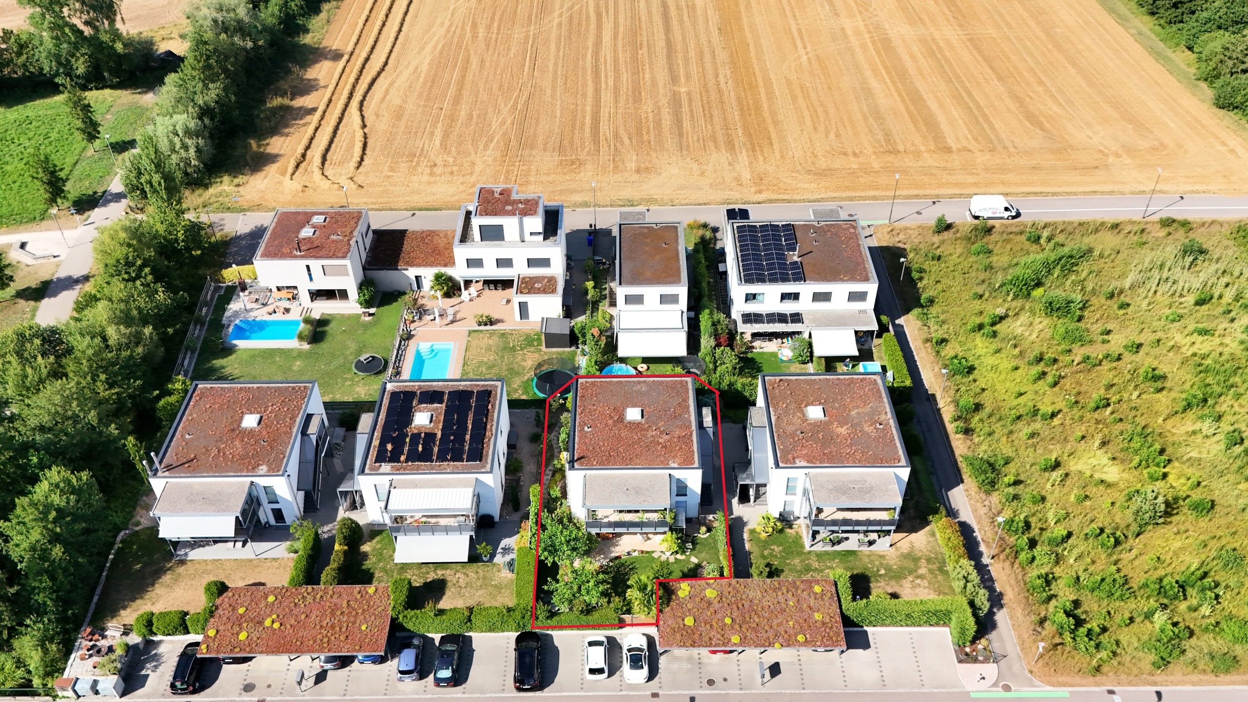 Luftaufnahme einer modernen Wohnanlage mit Gärten, Pools und Solardächern