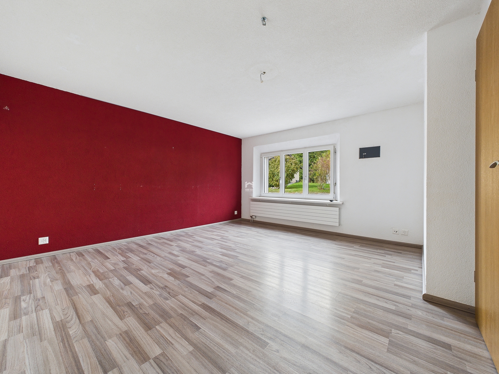 Leerer Raum mit roter Akzentwand und Fenster