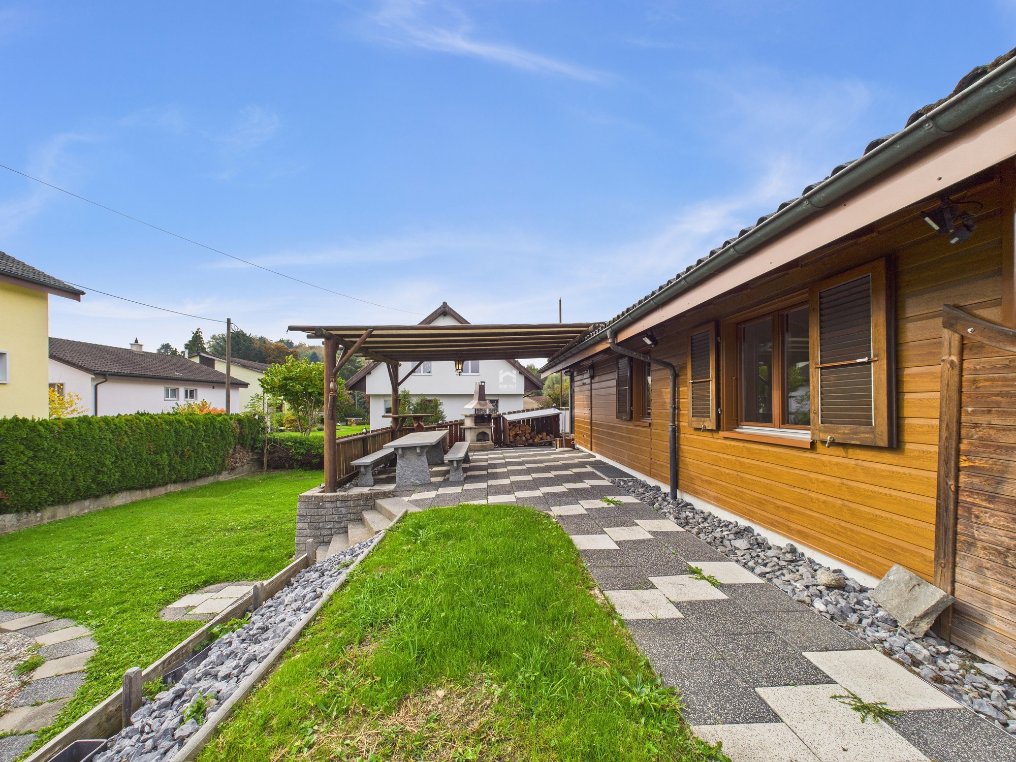 Außenansicht einer Terrasse mit Holzverkleidung und Garten