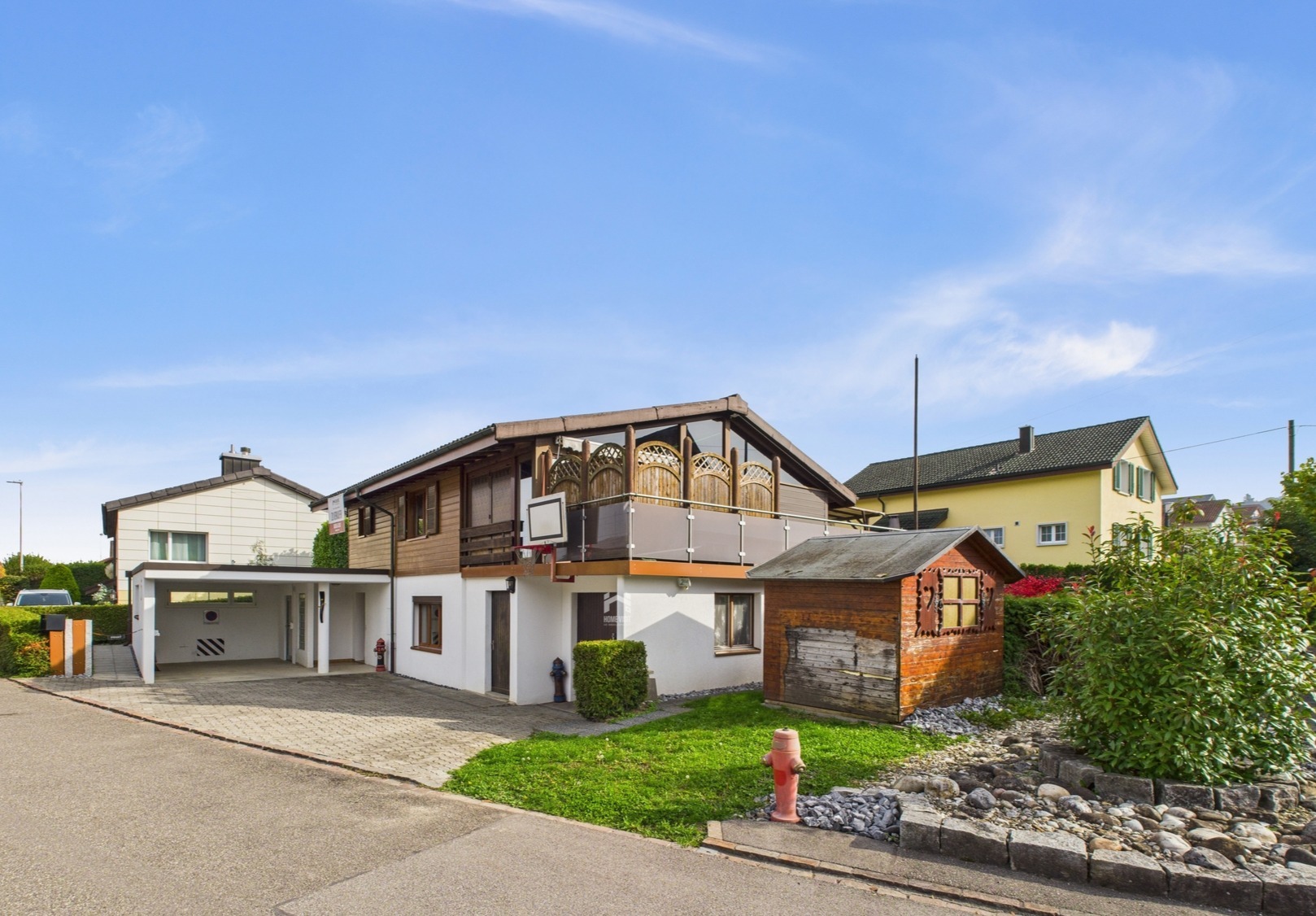 Außenansicht eines Wohnhauses mit Carport und Holzschuppen