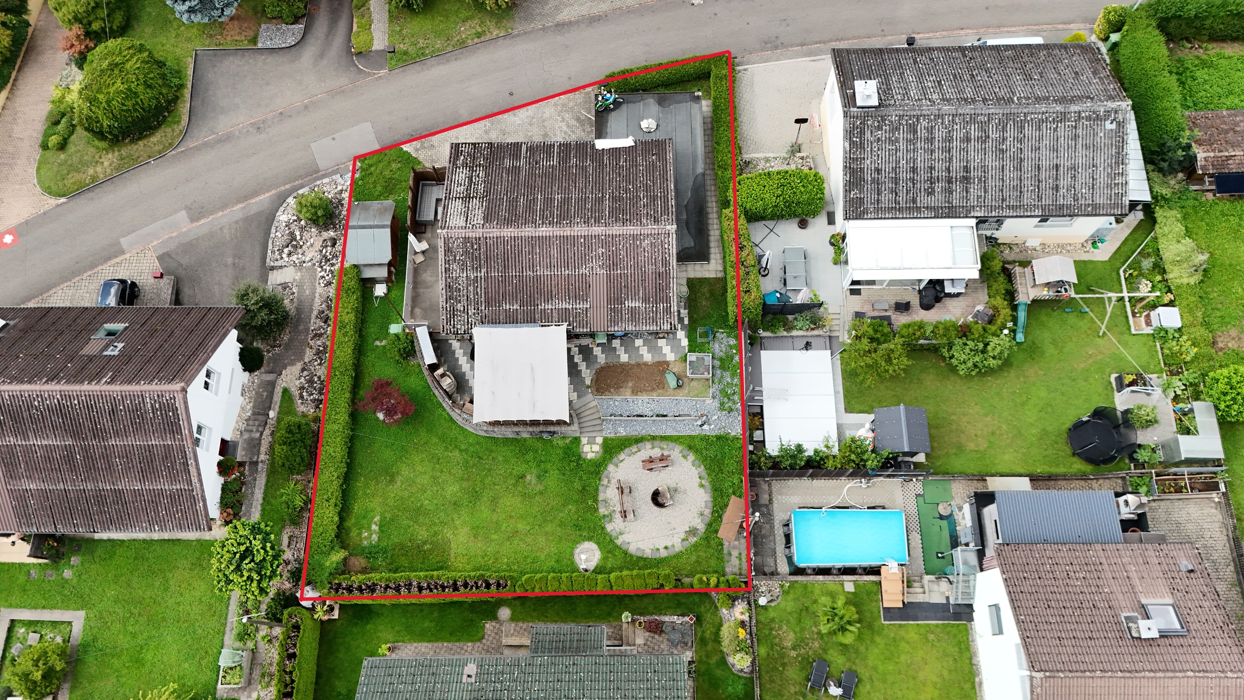 Luftaufnahme eines eingegrenzten Wohngrundstücks mit Garten, Terrasse und Nebengebäuden