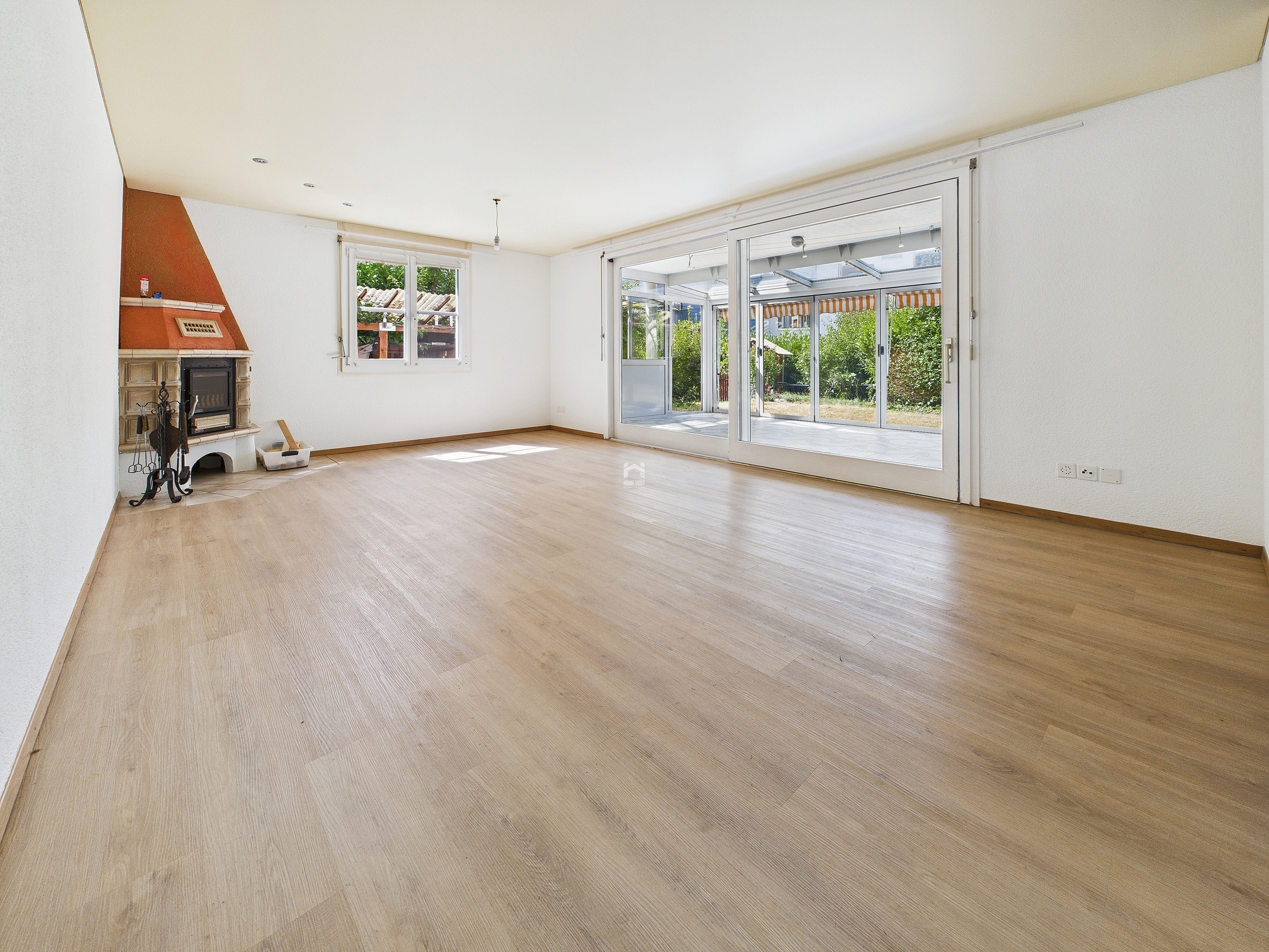 Heller Wohnraum mit Kamin und Wintergartenzugang